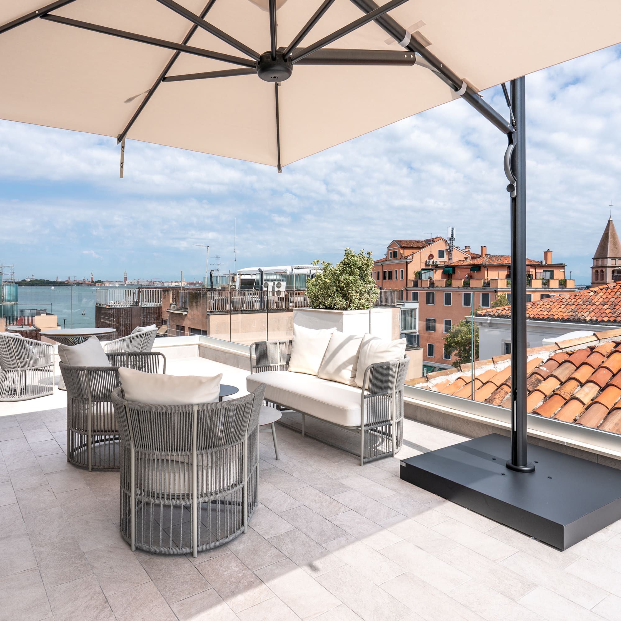 Rooftop terrace with modern outdoor furniture, umbrella, and Venice city view.