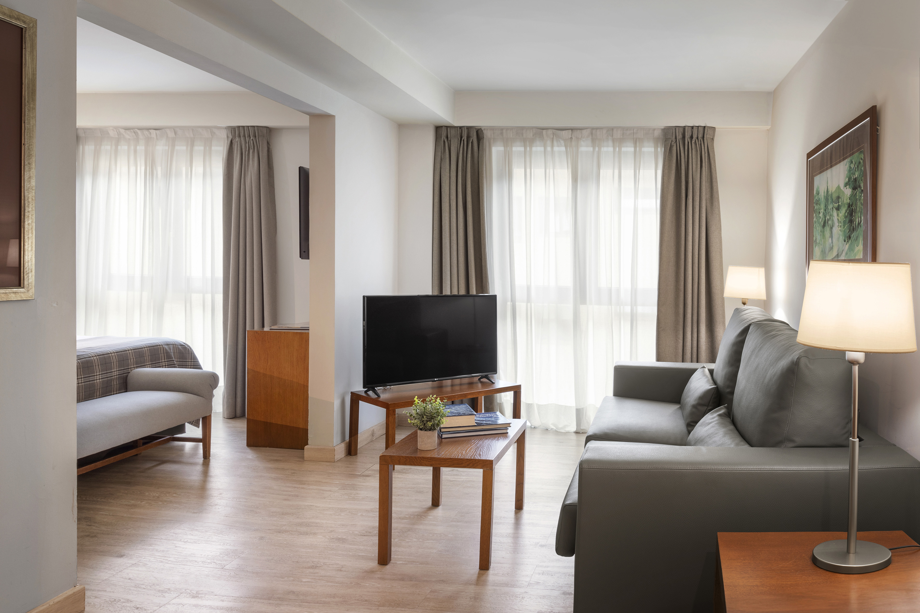 Hotel suite living room with sofa, TV, modern decor, and wood floors.