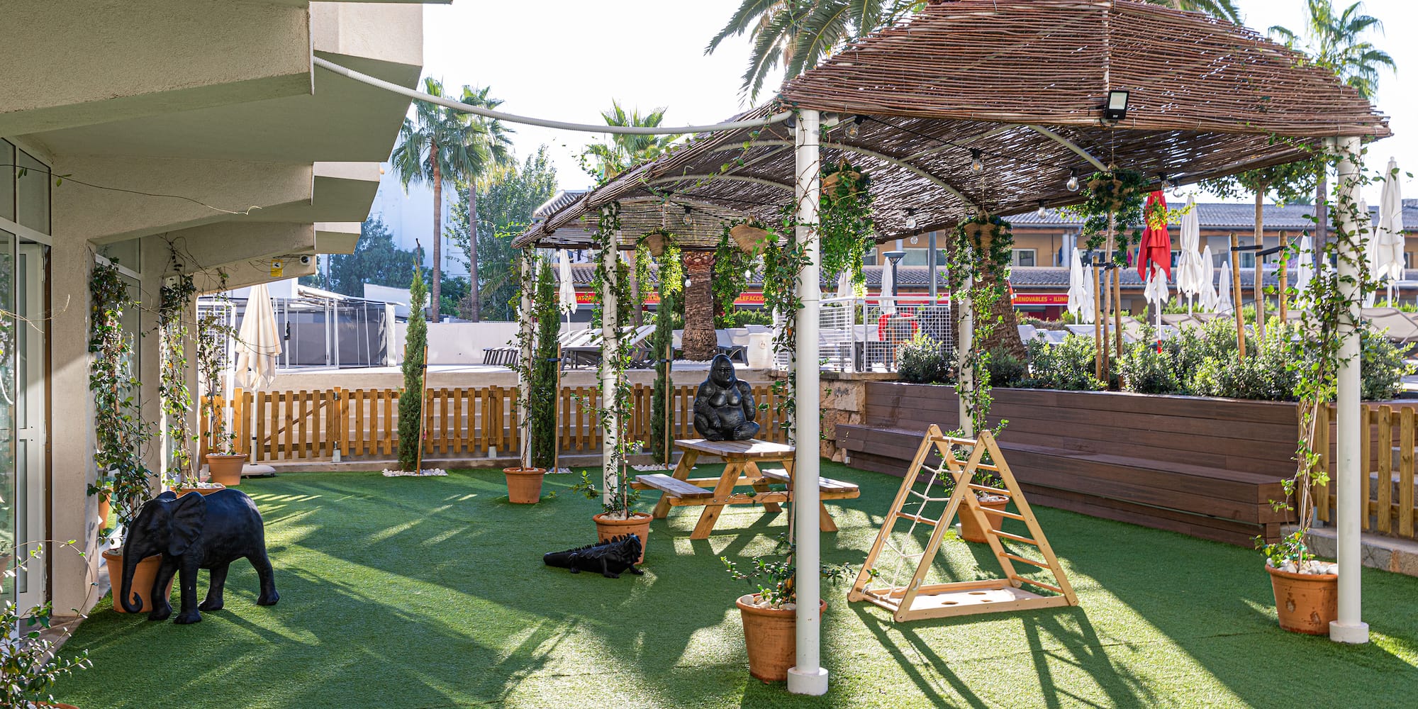 Shaded artificial grass patio with picnic table and kids' play area.