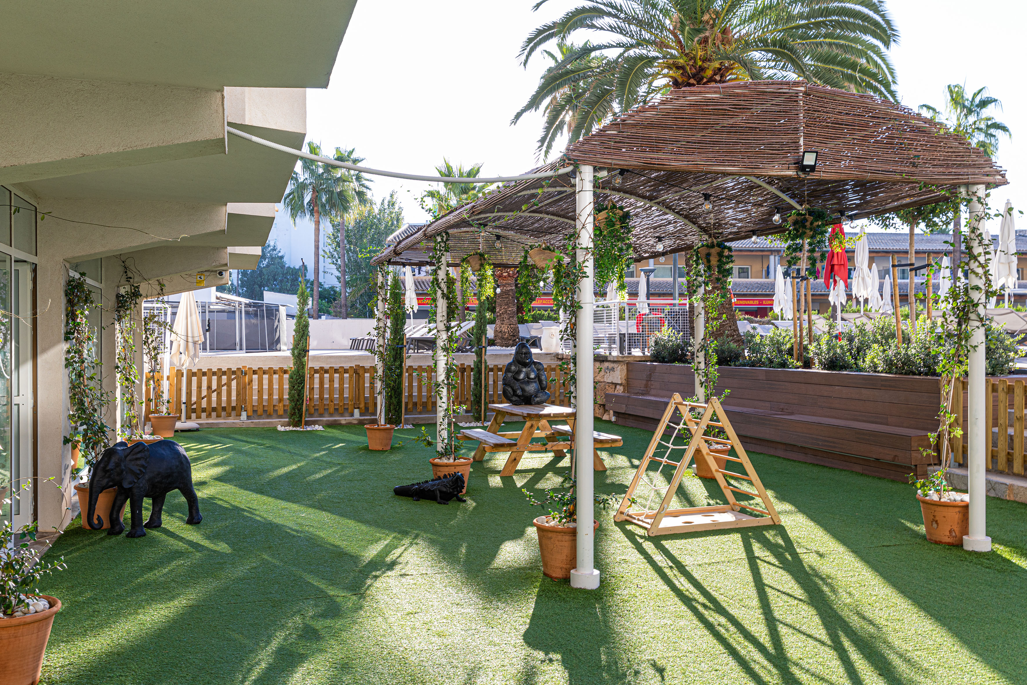 Shaded artificial grass patio with picnic table and kids' play area.
