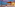 Illuminated beachfront restaurant with outdoor seating, sandy beach, and twilight sky.
