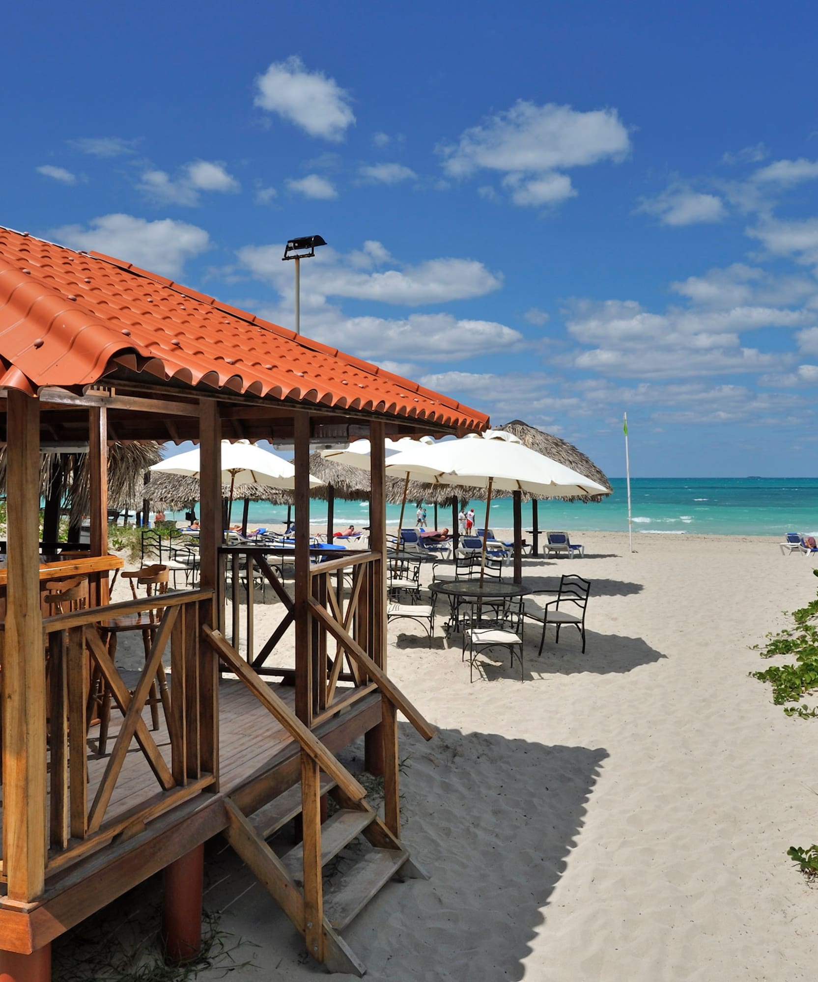 a beach with umbrellas and a gazebo