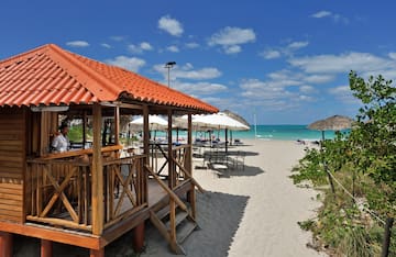 a beach with umbrellas and a gazebo