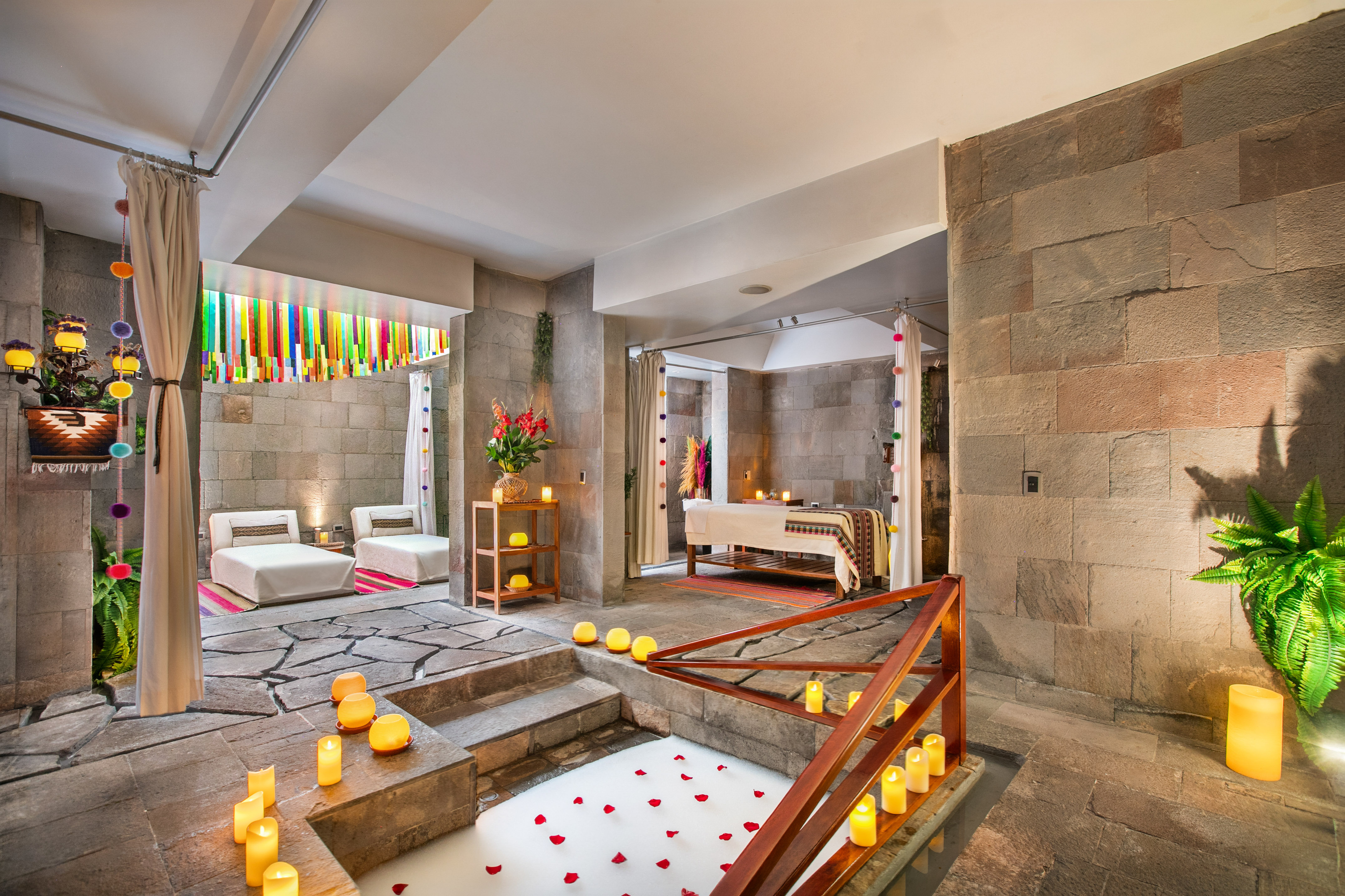 Andean luxury spa with stone walls, rose petal bath, and massage area.
