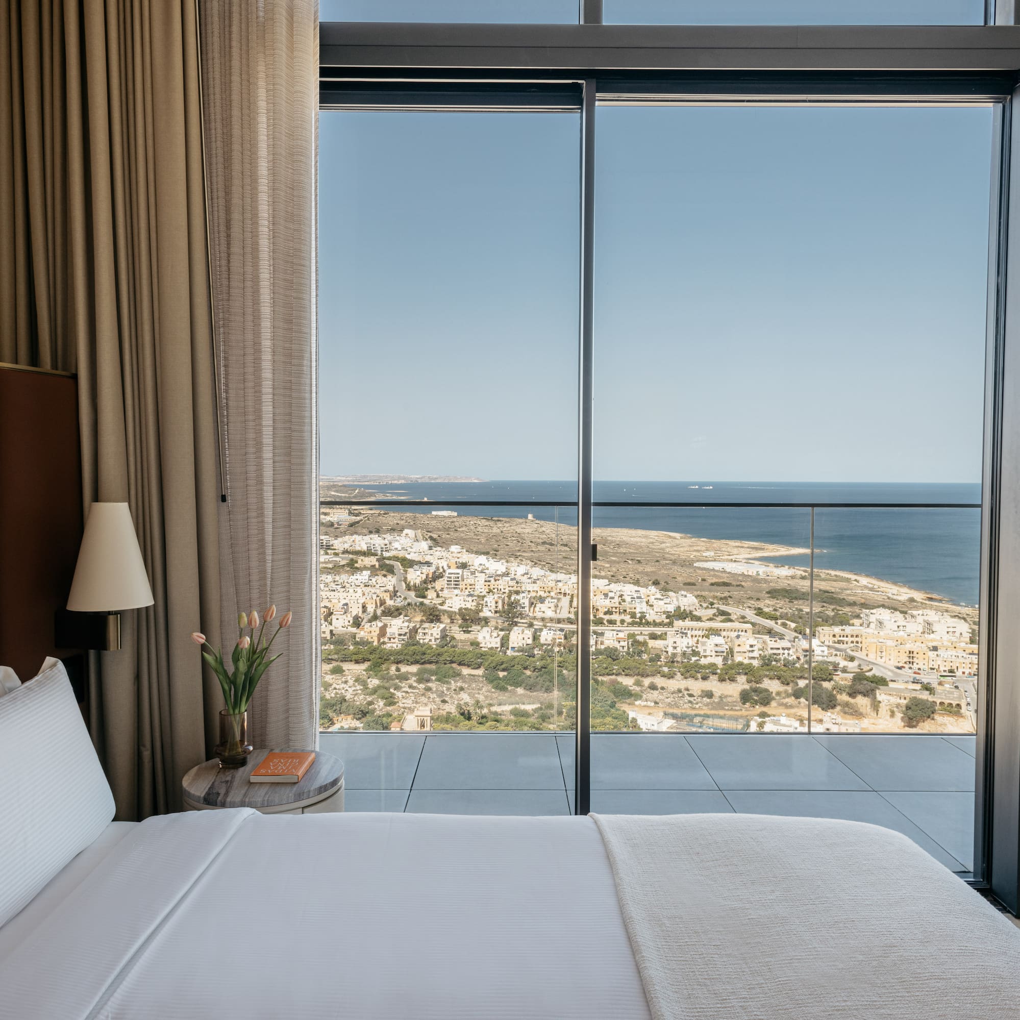 a bed with a view of the ocean and a city