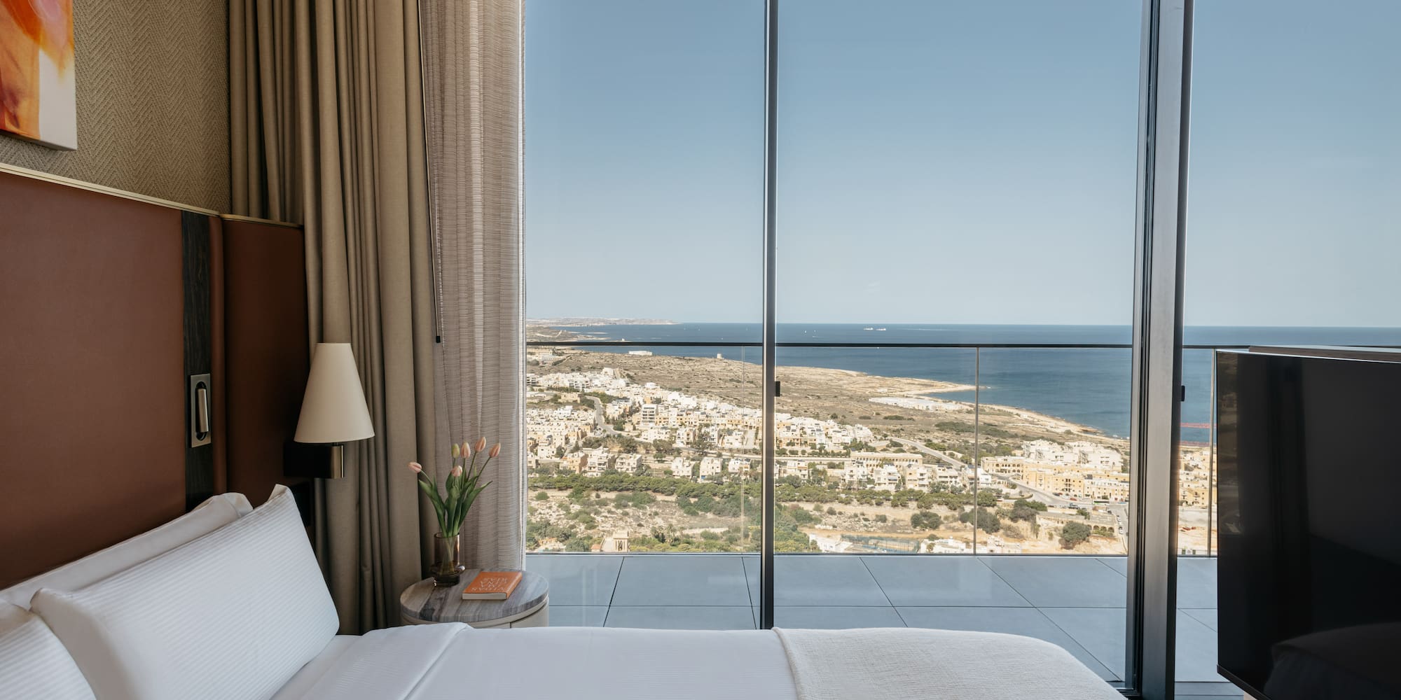 a bed with a view of the ocean and a city