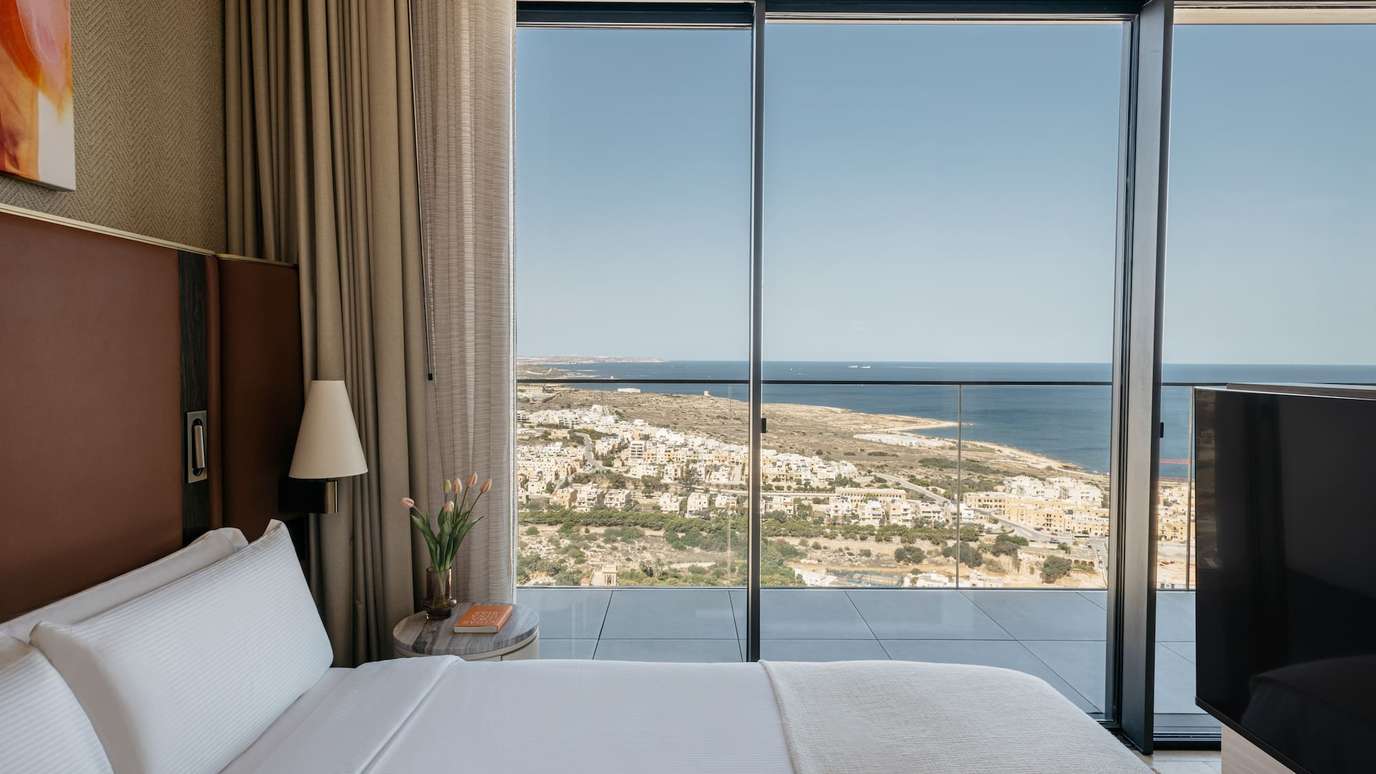 a bed with a view of the ocean and a city