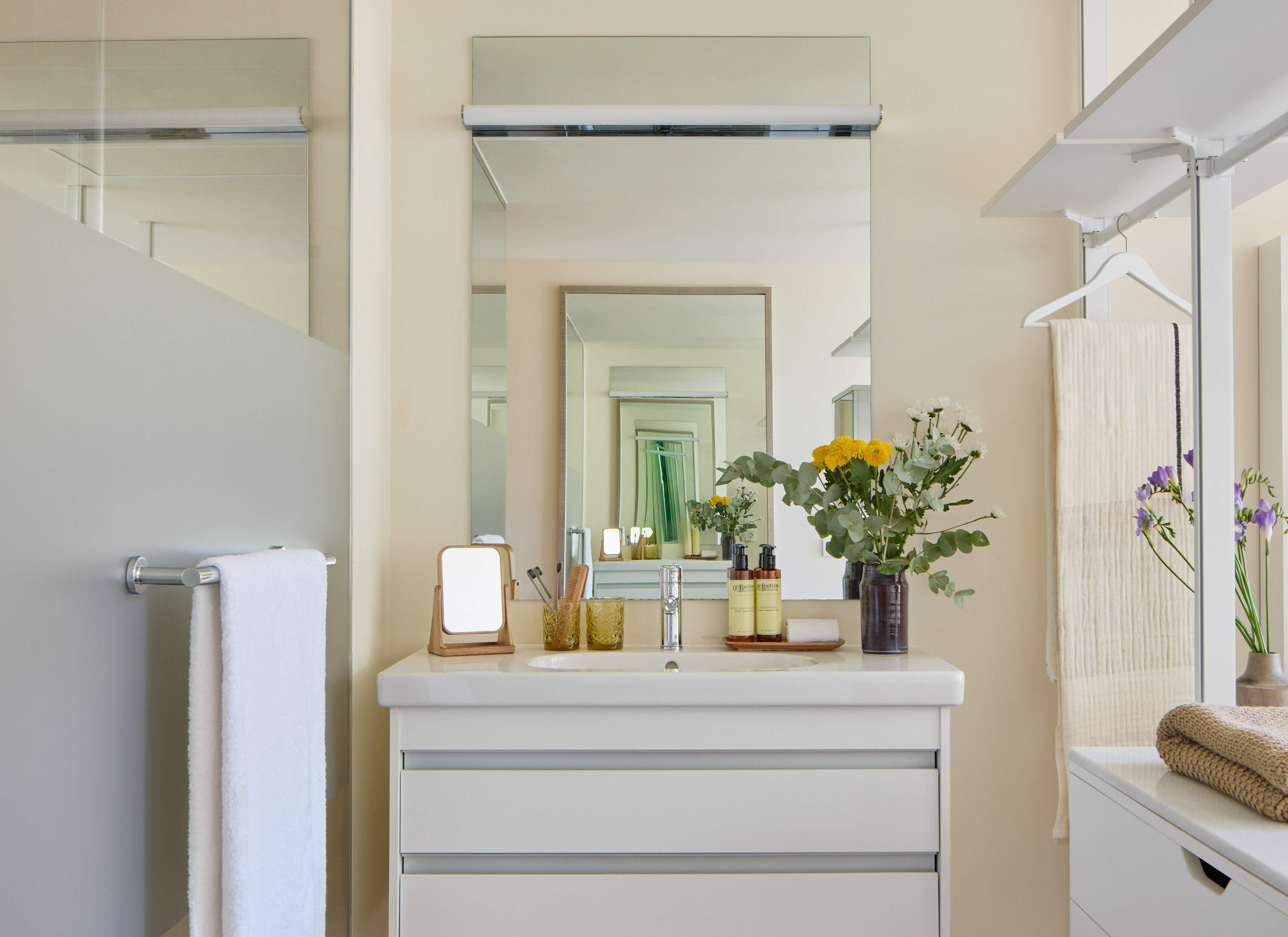 Modern bathroom vanity with white drawers, sink, mirror, and floral accents.