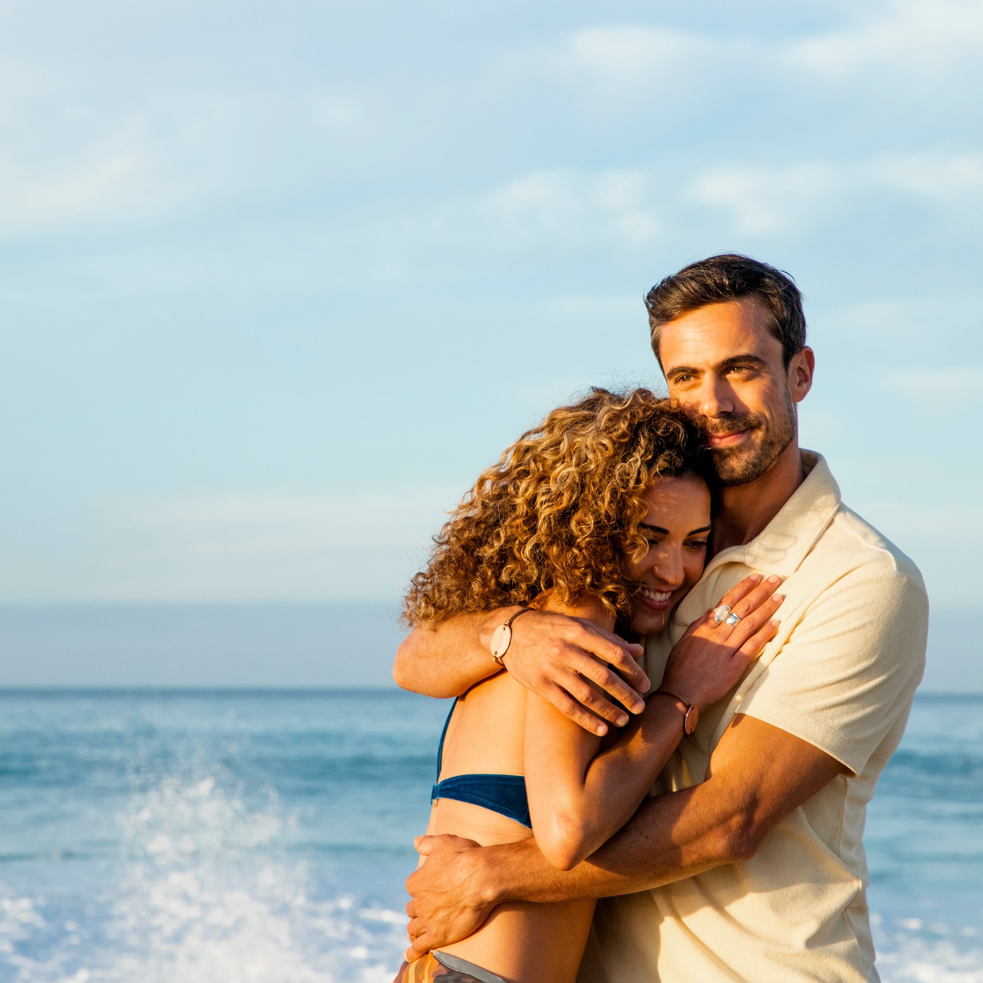 a man and woman hugging on a beach