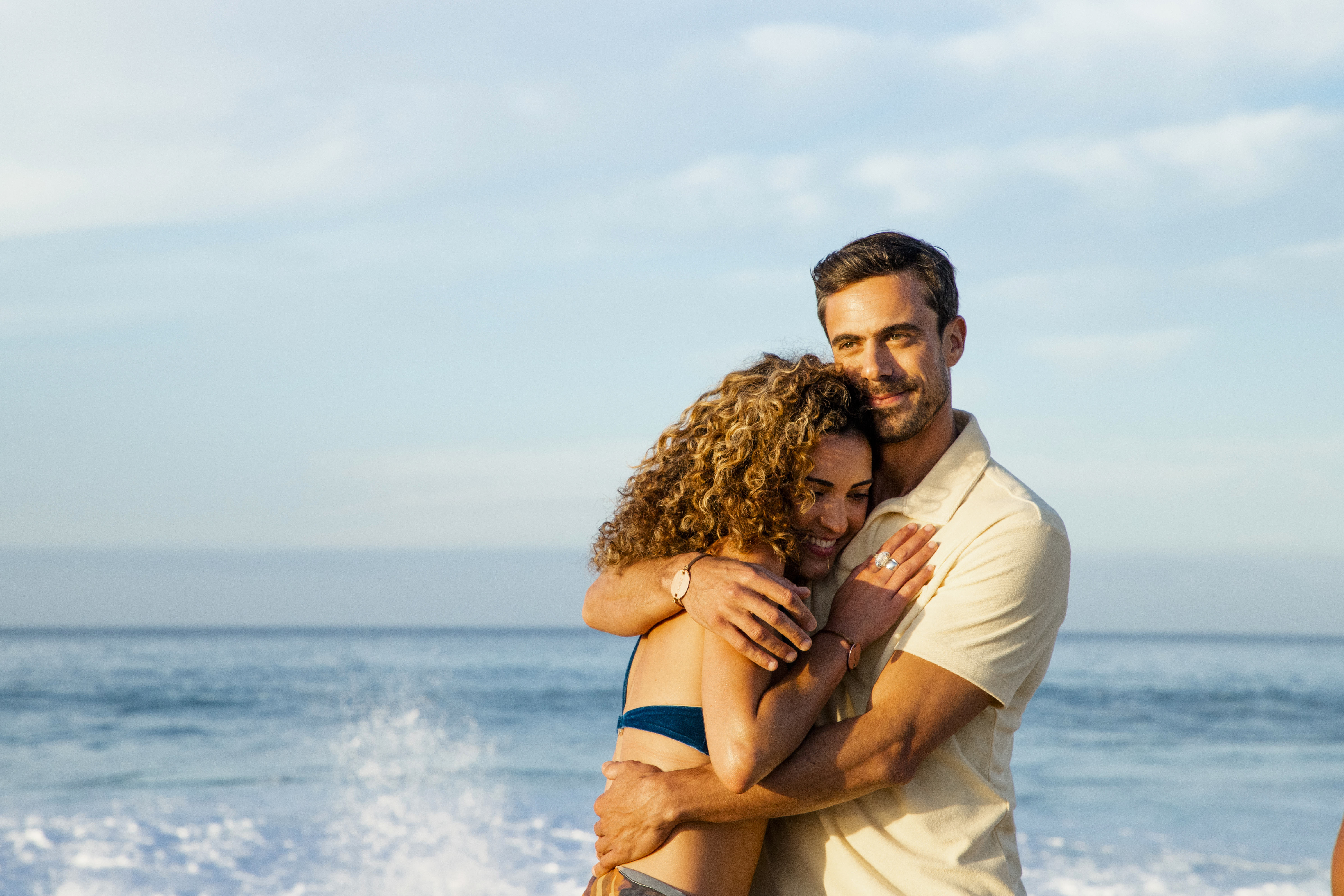 a man and woman hugging on a beach