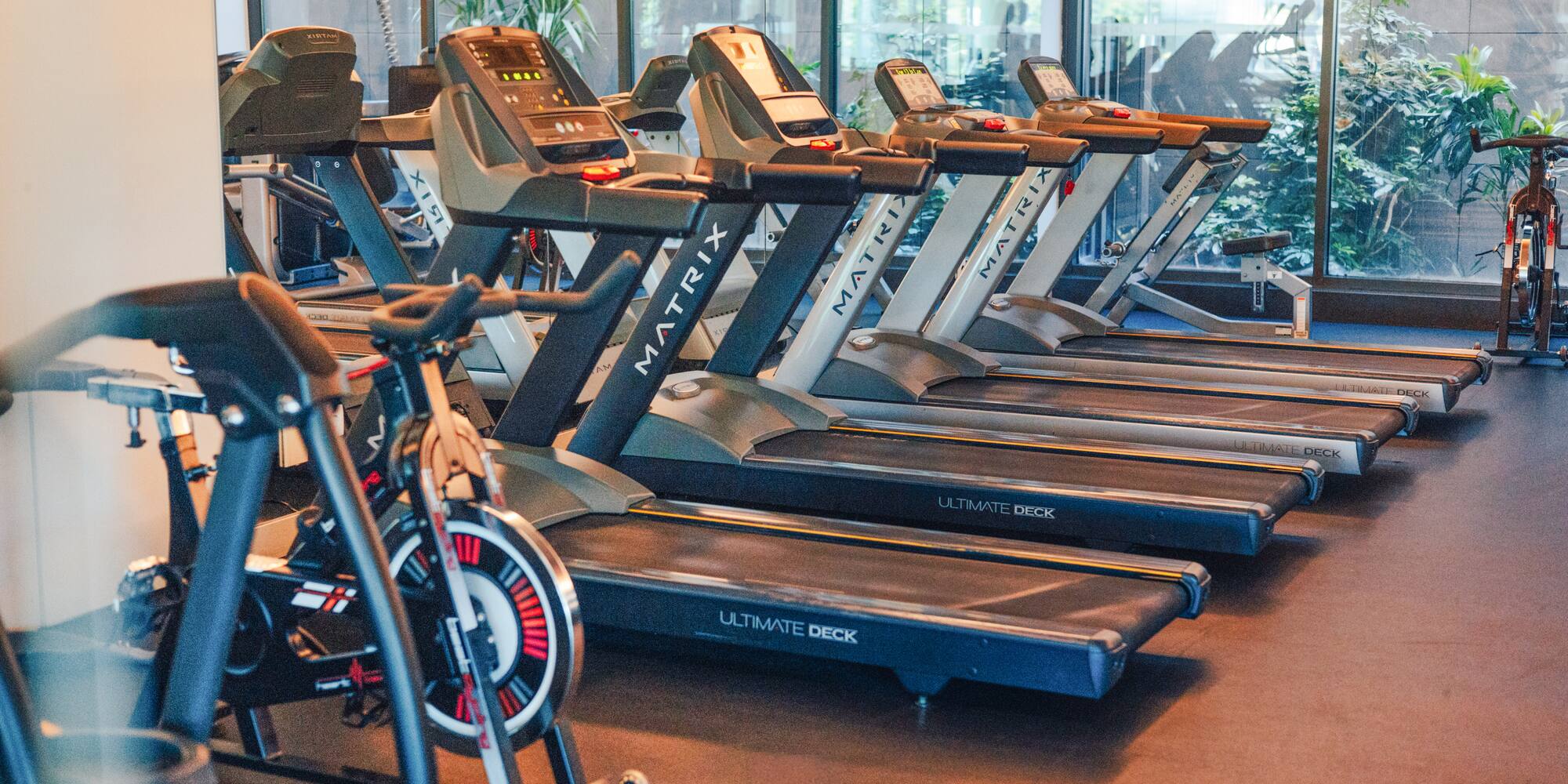 Matrix Ultimate Deck treadmills and exercise bike in a modern gym.