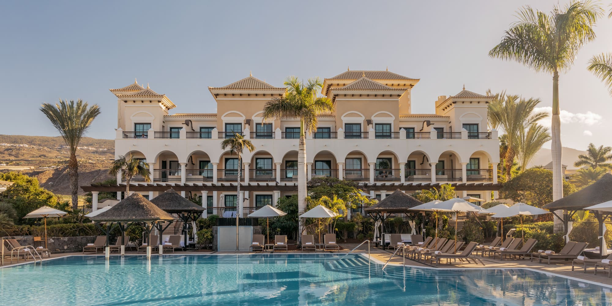a pool with umbrellas and a building with balconies