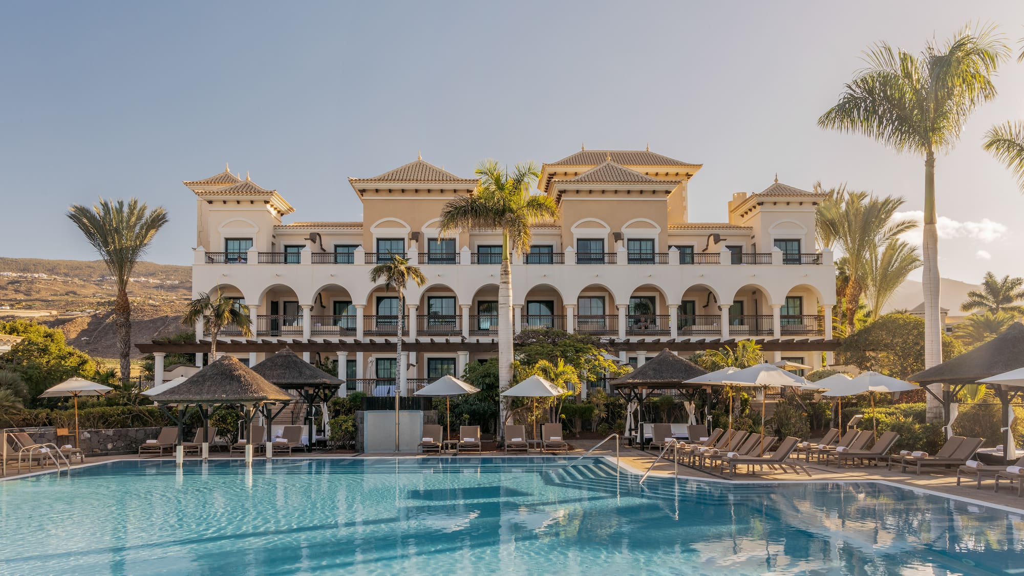 a pool with umbrellas and a building with balconies