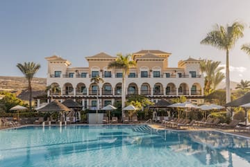 a pool with umbrellas and a building with balconies