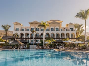 a pool with umbrellas and a building with balconies