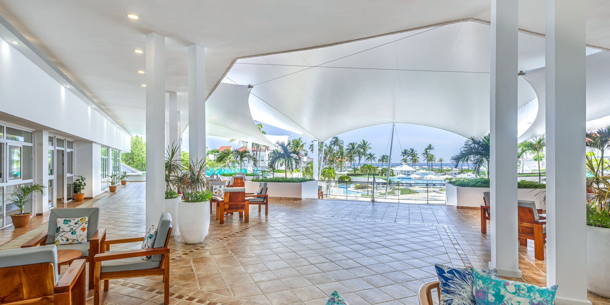 a large white room with chairs and a pool in the background