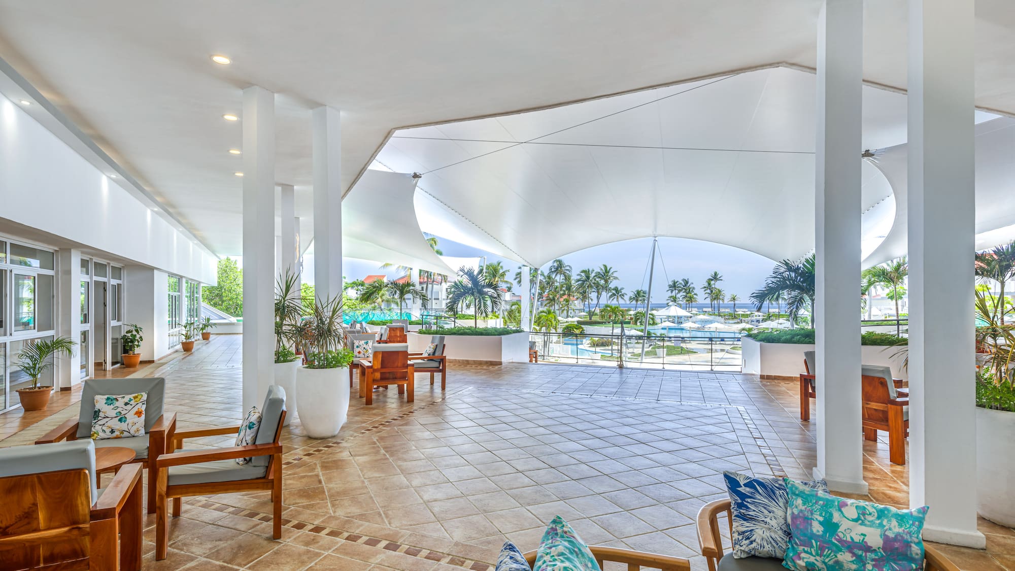 a large white room with chairs and a pool in the background