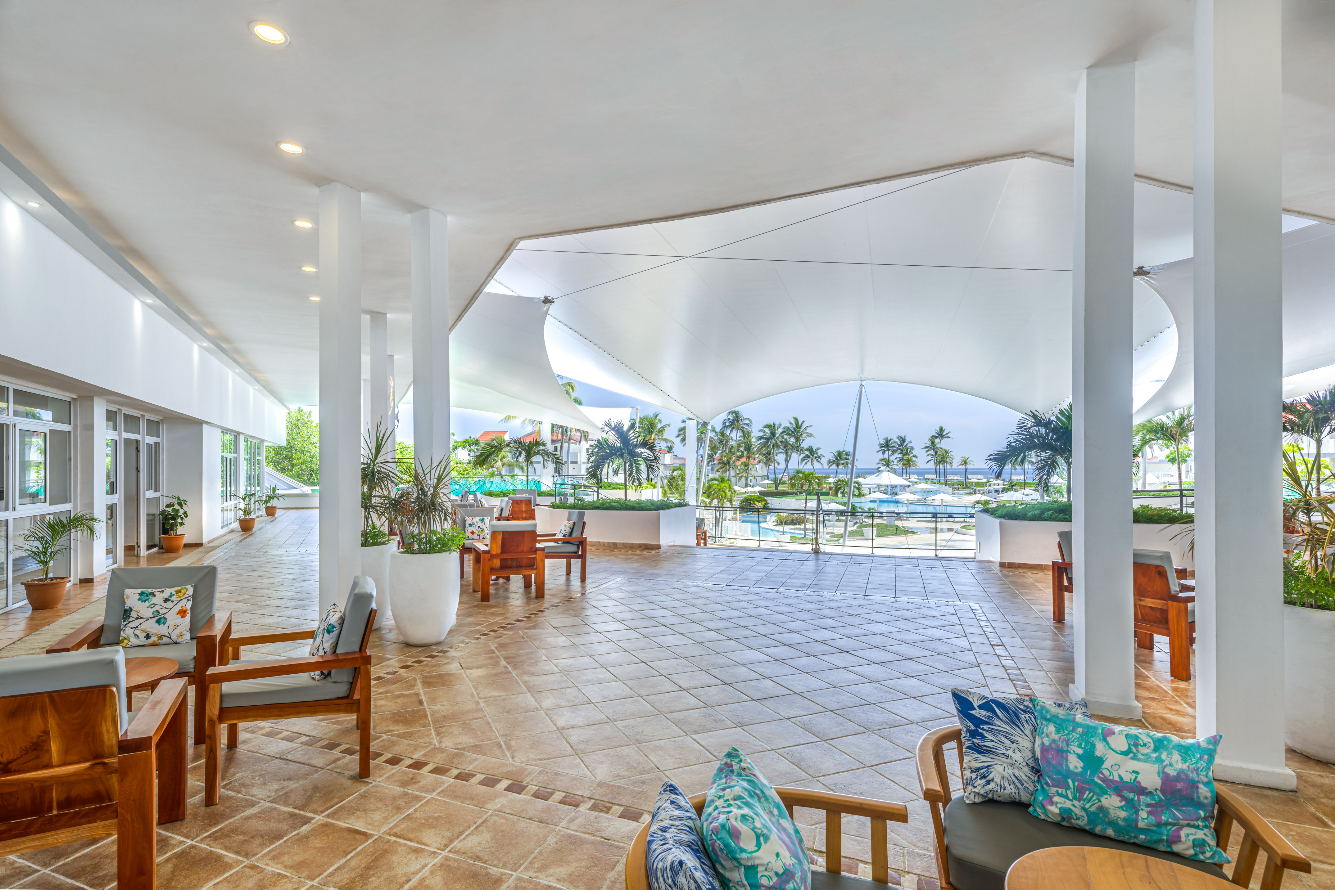 a large white room with chairs and a pool in the background