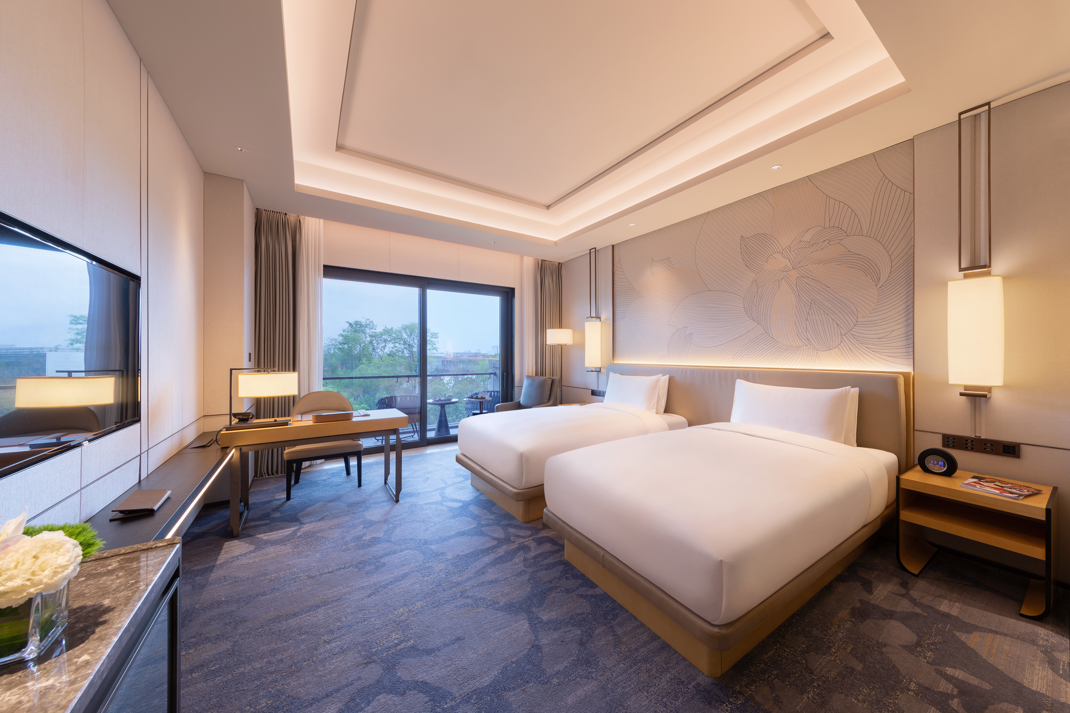 Modern hotel twin room with work desk, balcony access, and contemporary design.