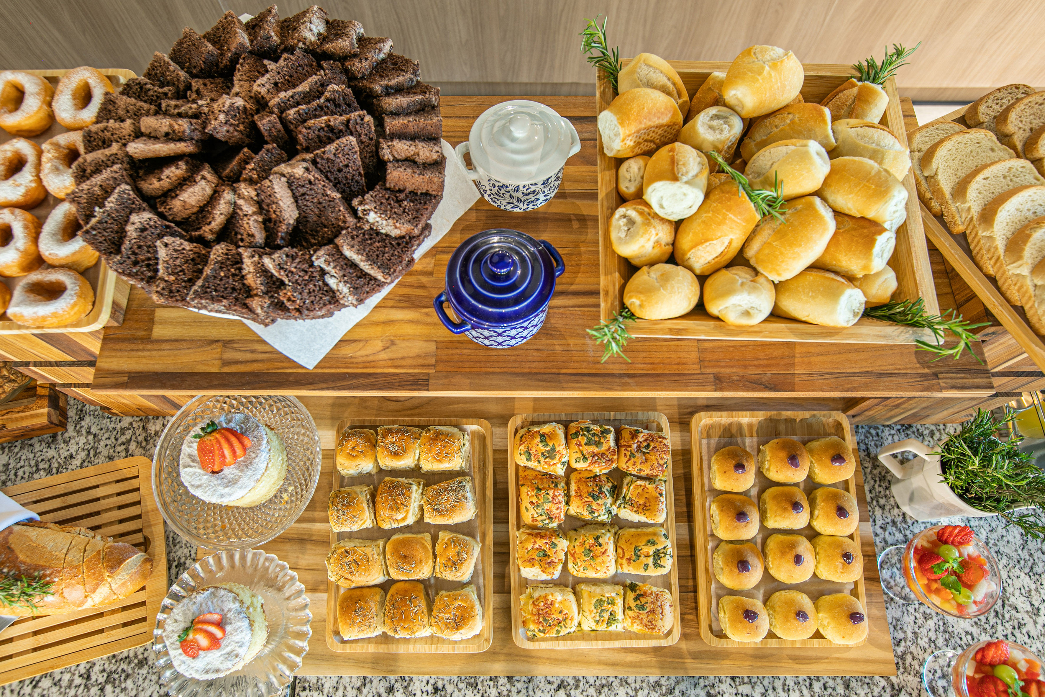 Breakfast buffet with assorted baked goods, chocolate cake, donuts, and fruit.