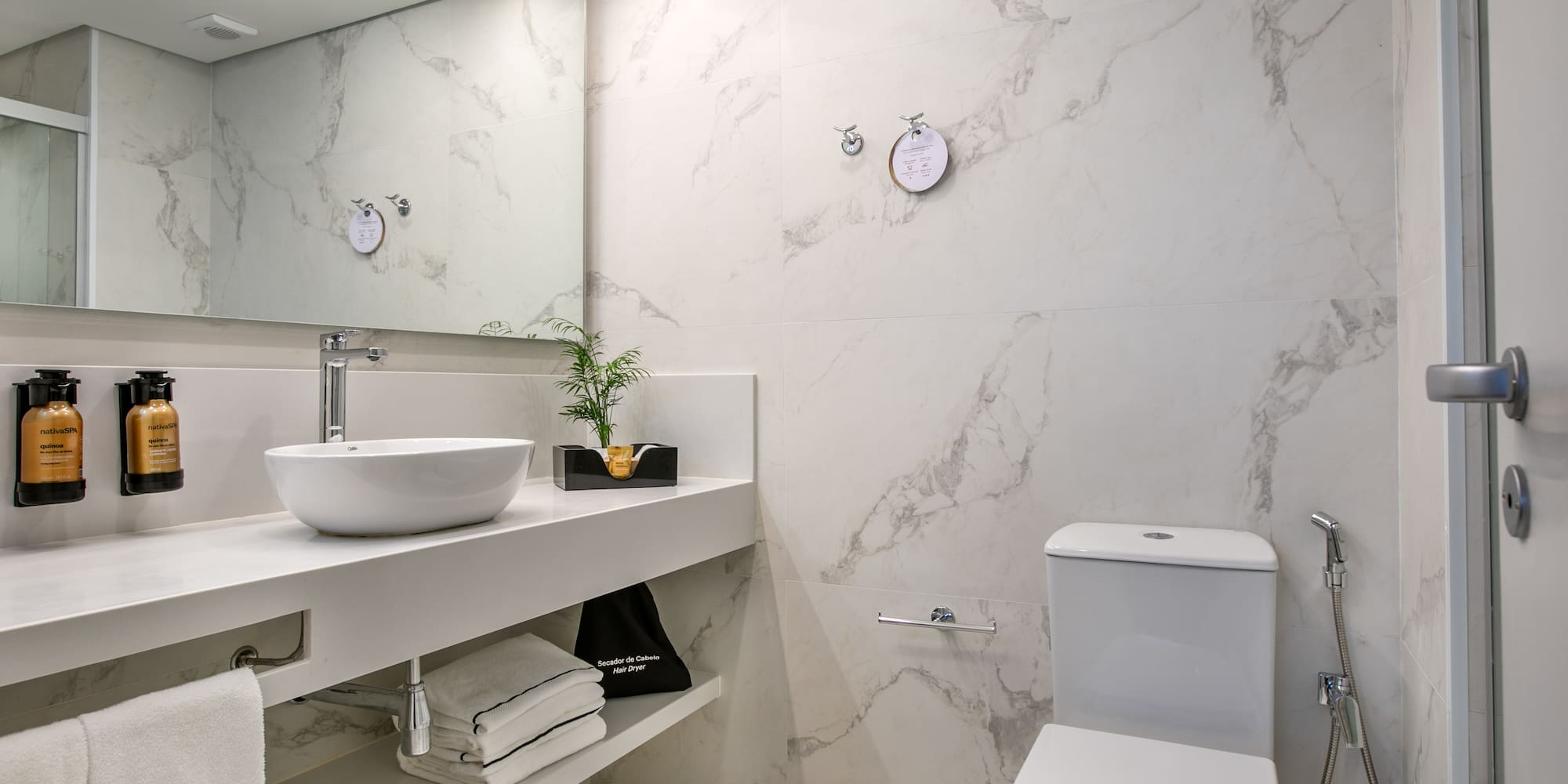 Clean modern bathroom with white marble, vessel sink, vanity, and toilet.