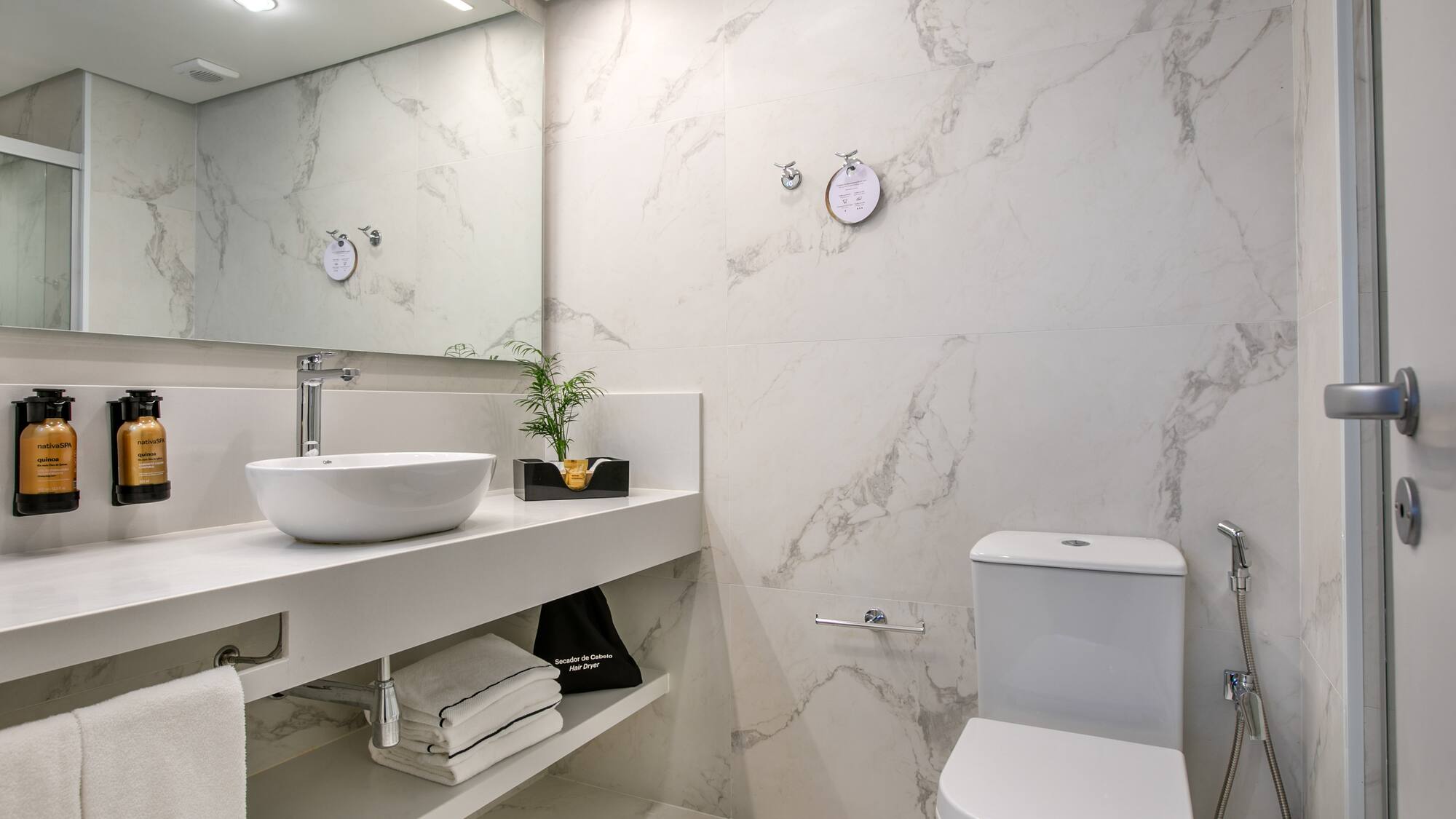 Clean modern bathroom with white marble, vessel sink, vanity, and toilet.