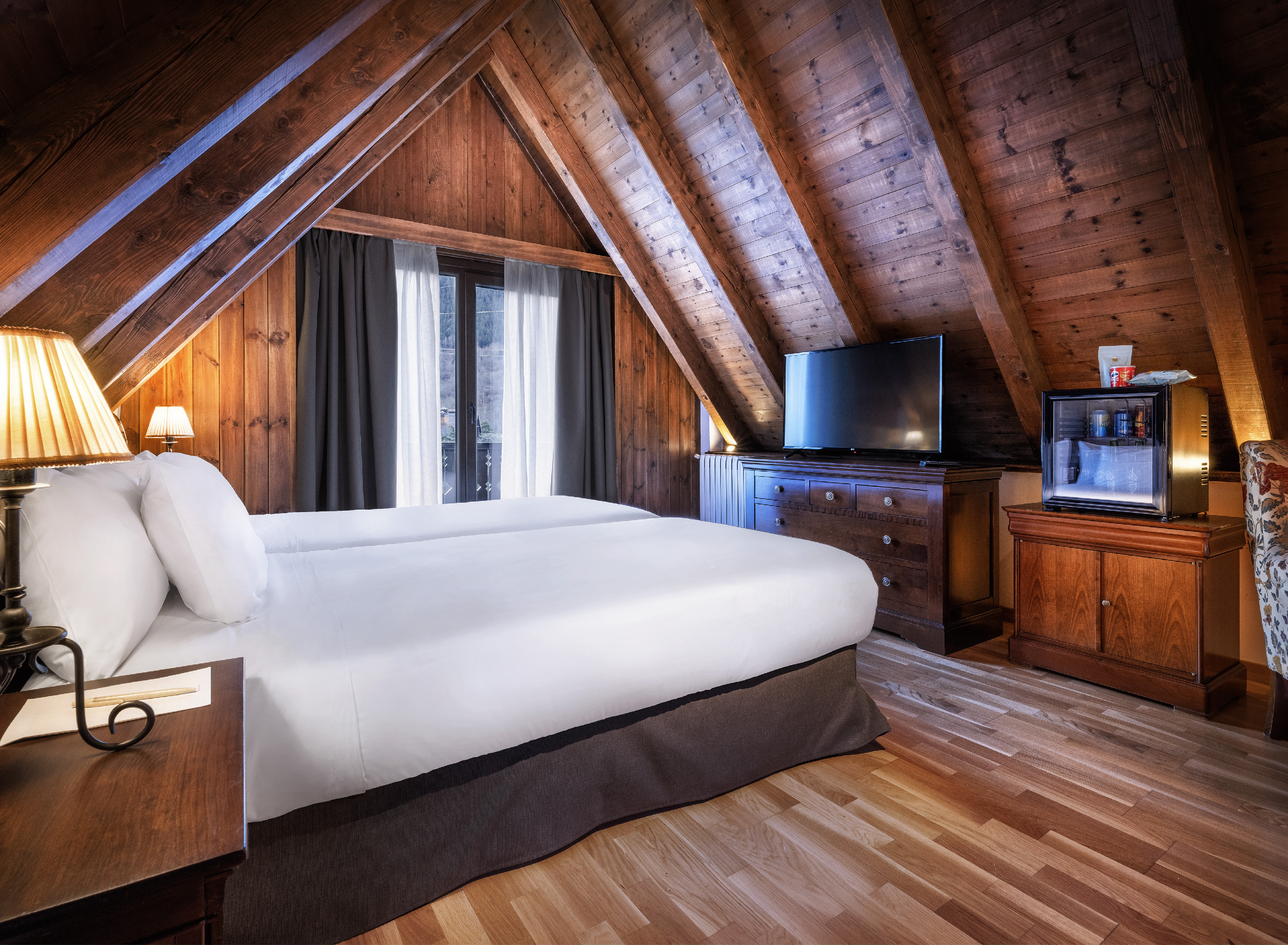 Chalet style attic room with wood paneling, twin beds, and a TV.