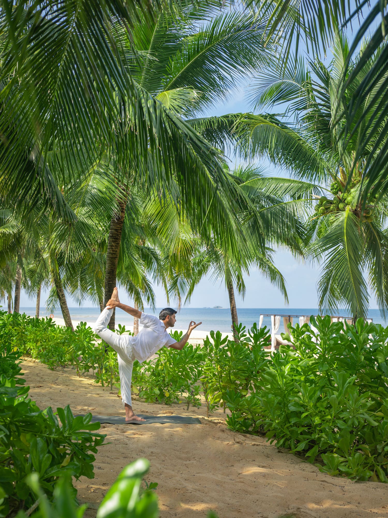 a man doing yoga on a beach