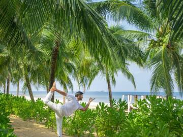 a man doing yoga on a beach