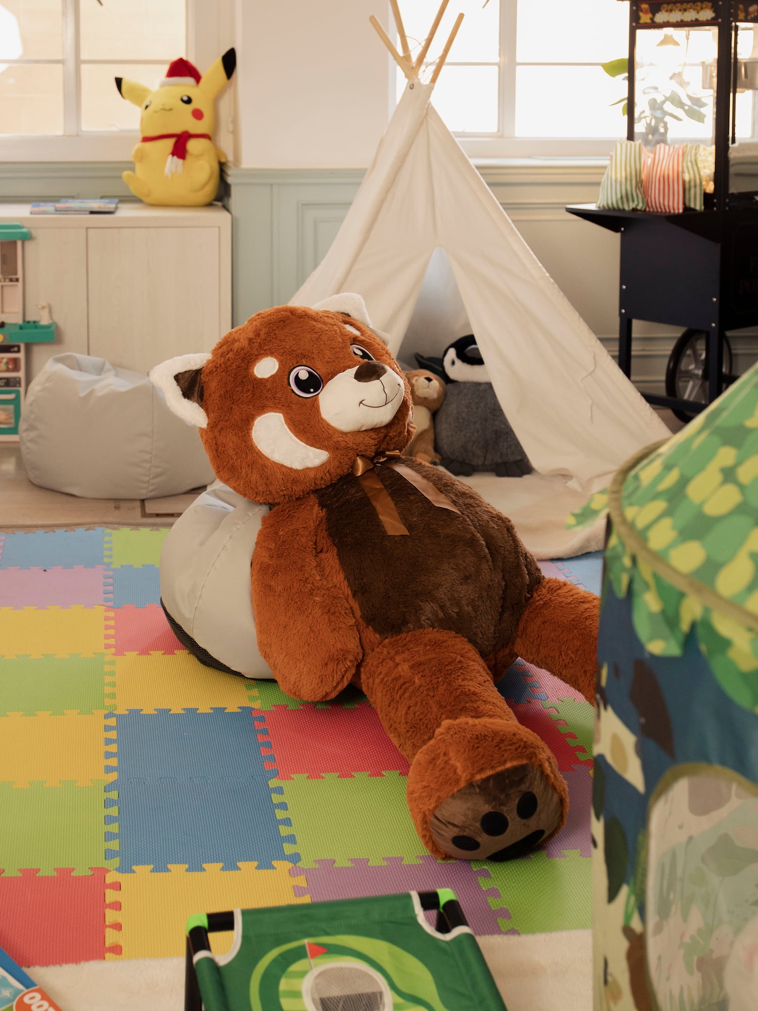 Large red panda plush toy in a colorful kids' playroom with teepee and toys.