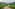 Winding road through green rice terraces, rural village, and misty mountains.