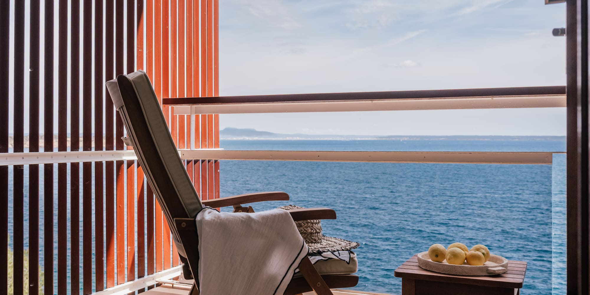 a chair and table on a balcony overlooking the ocean