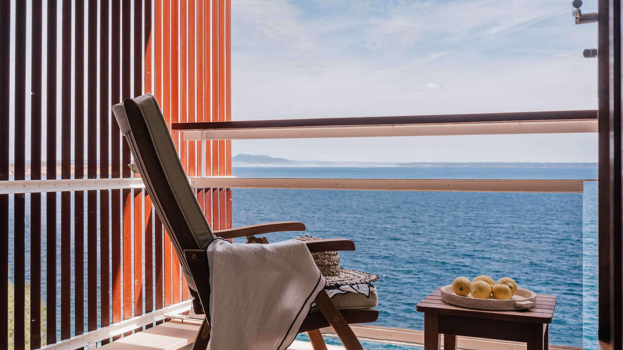 a chair and table on a balcony overlooking the ocean