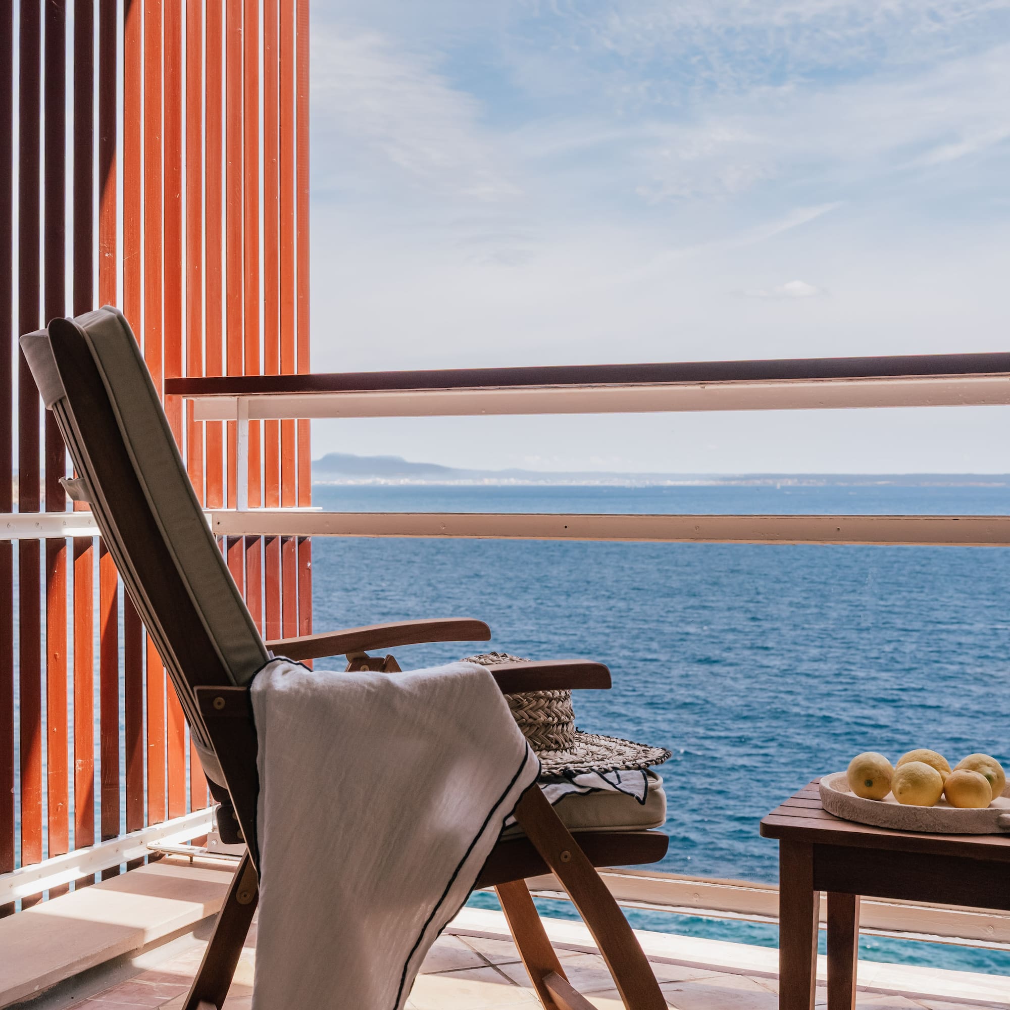 a chair and table on a balcony overlooking the ocean