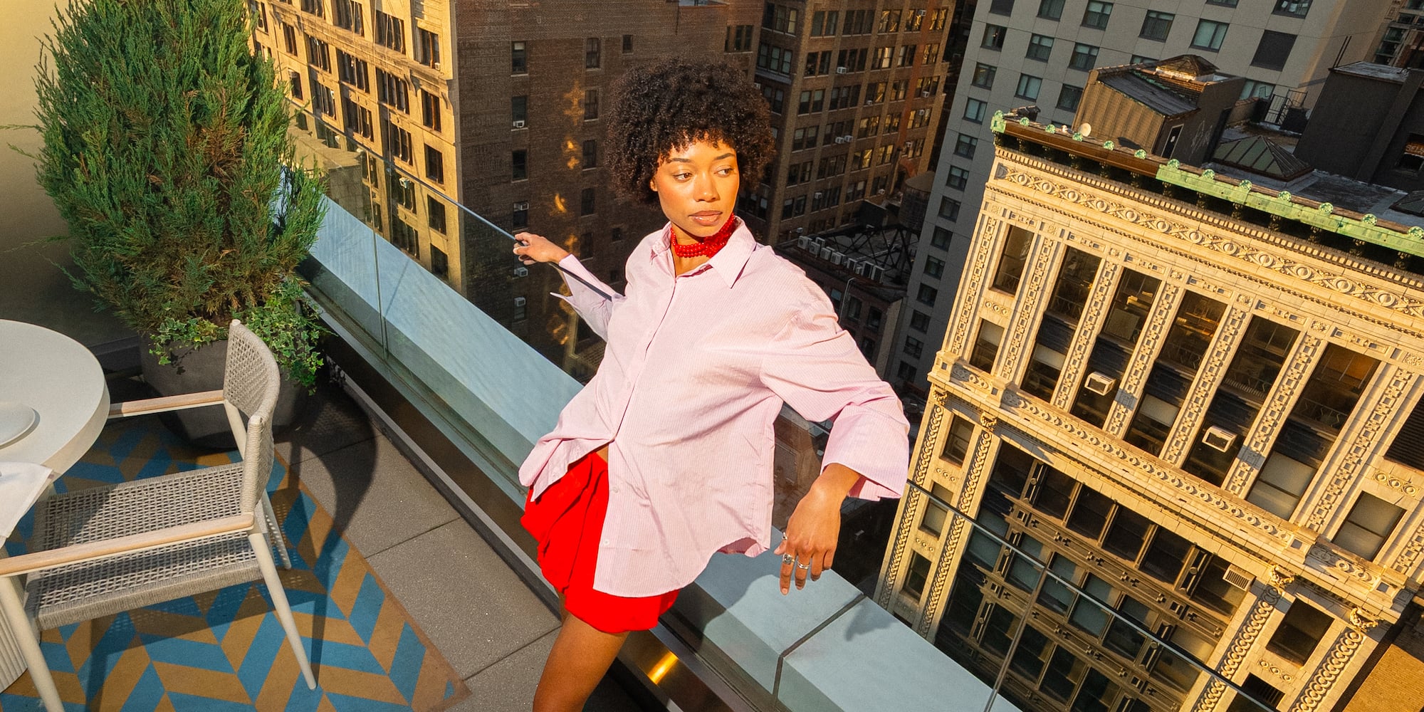 a woman standing on a balcony with a city in the background