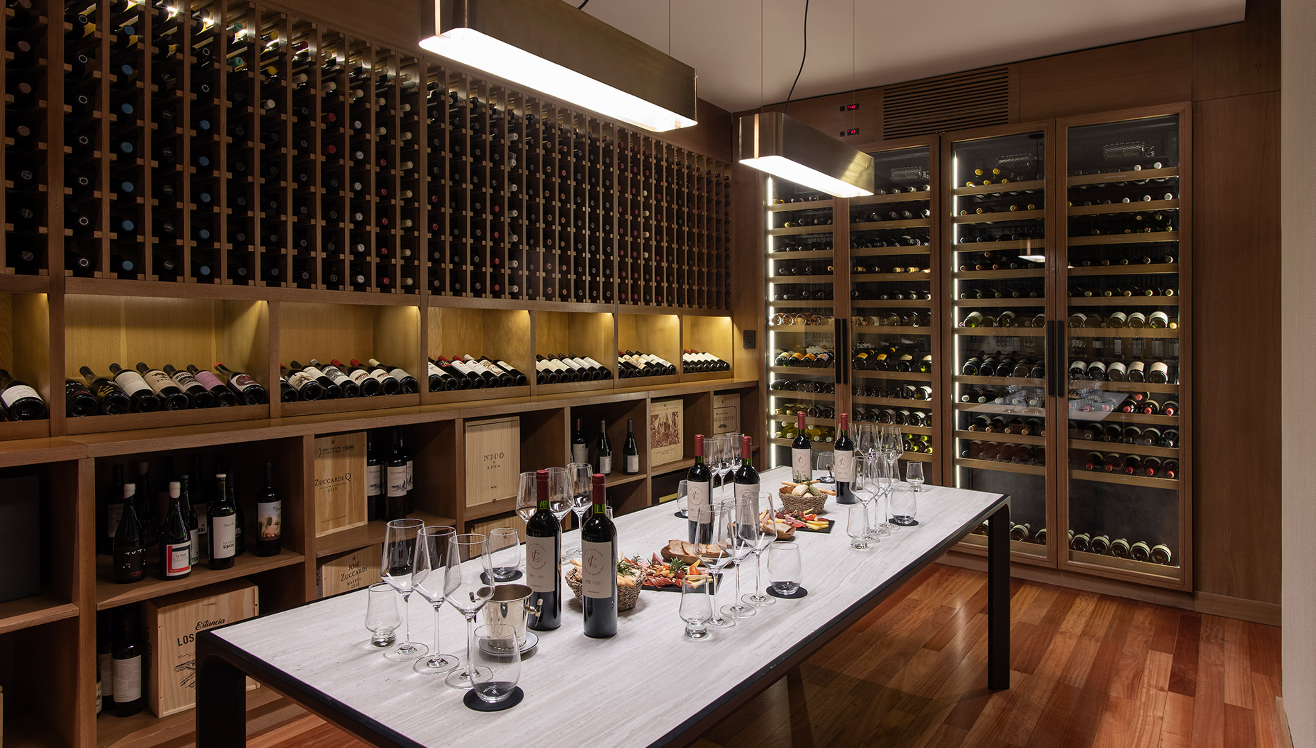 Elegant wine cellar with wooden racks, glass wine coolers, and a tasting table.