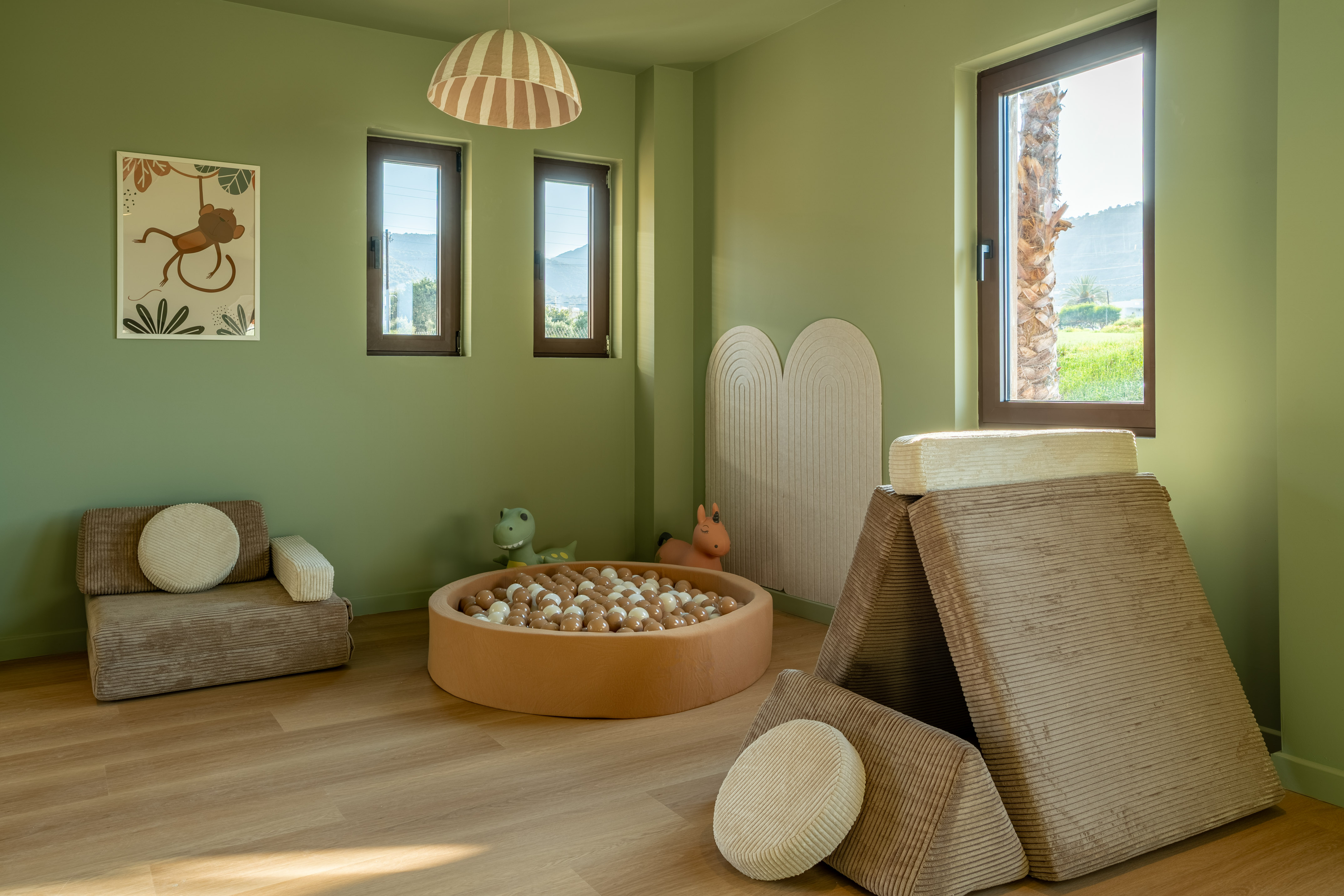 Green kids playroom with ball pit, modular soft play furniture, and jungle decor.