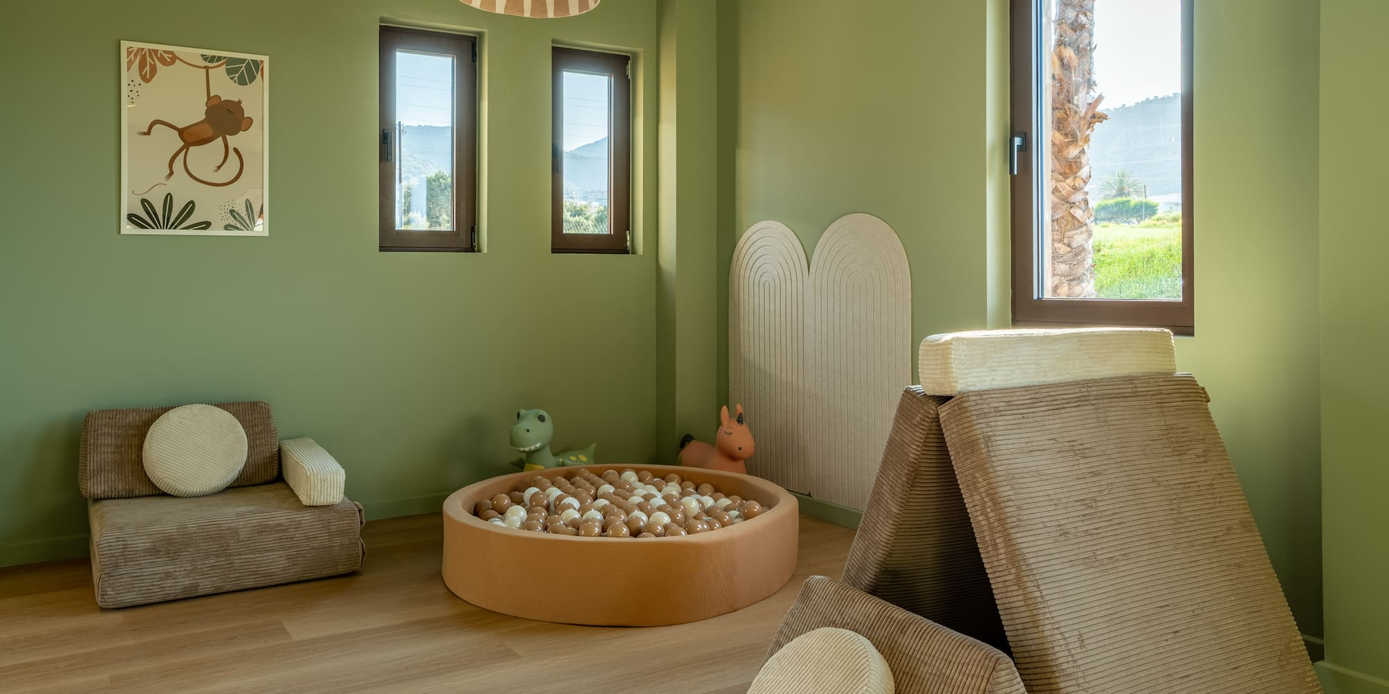 Green kids playroom with ball pit, modular soft play furniture, and jungle decor.