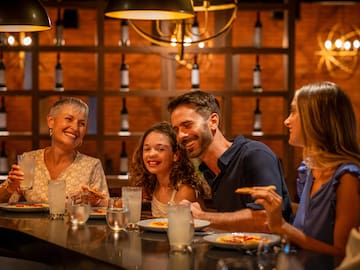 a group of people sitting at a table eating pizza