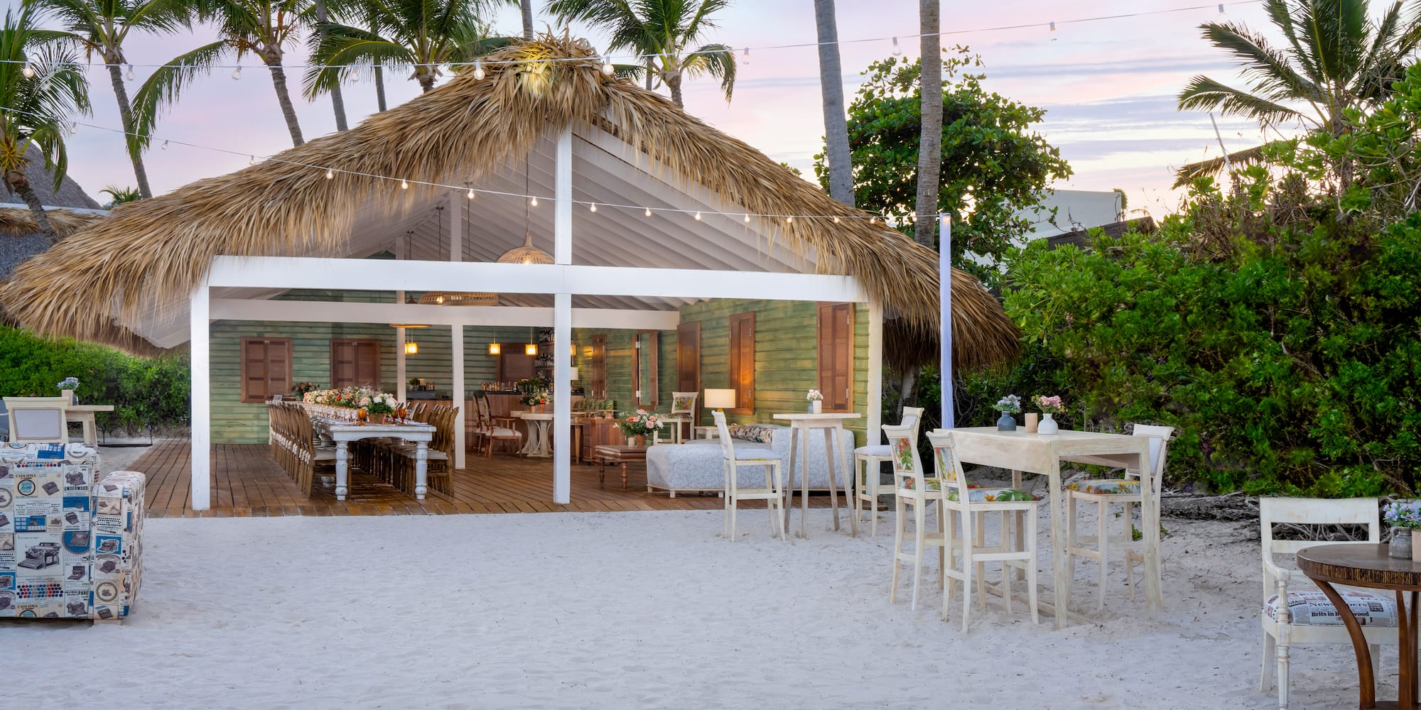 a hut with tables and chairs on a beach