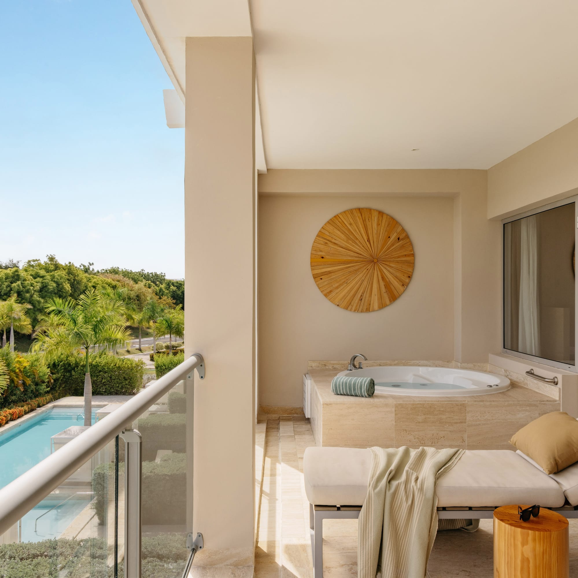 Luxury hotel balcony with private hot tub, daybed, and tropical pool view.