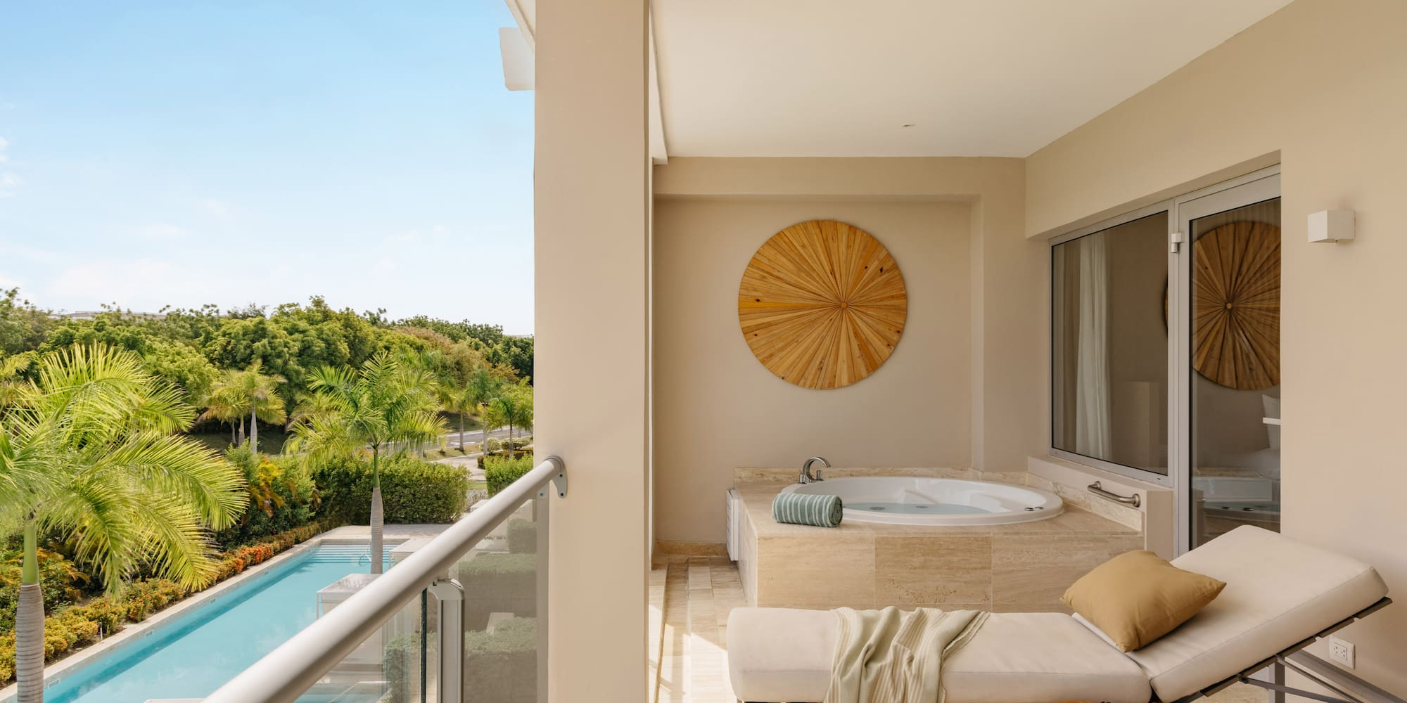 Luxury hotel balcony with private hot tub, daybed, and tropical pool view.