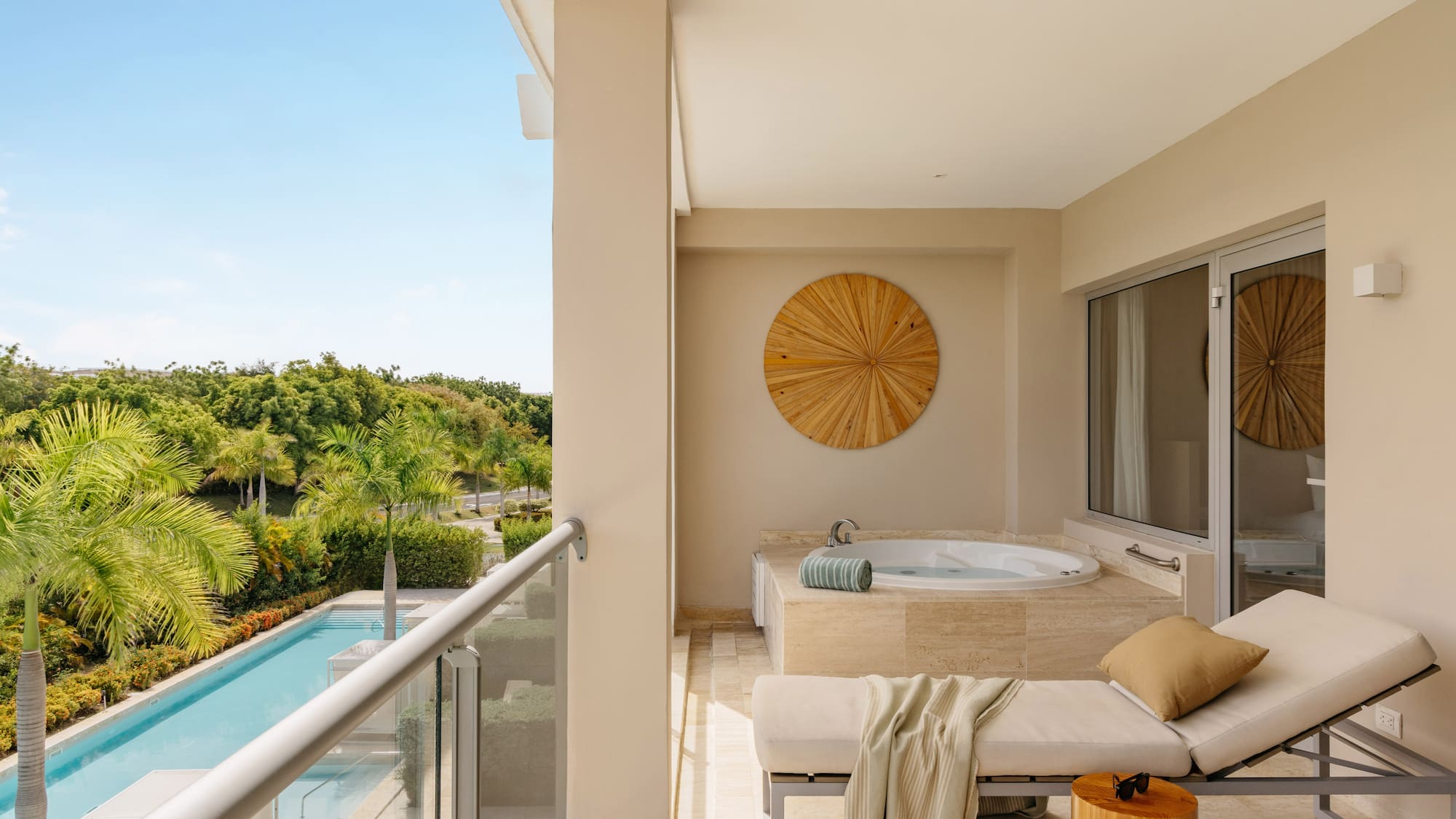 Luxury hotel balcony with private hot tub, daybed, and tropical pool view.