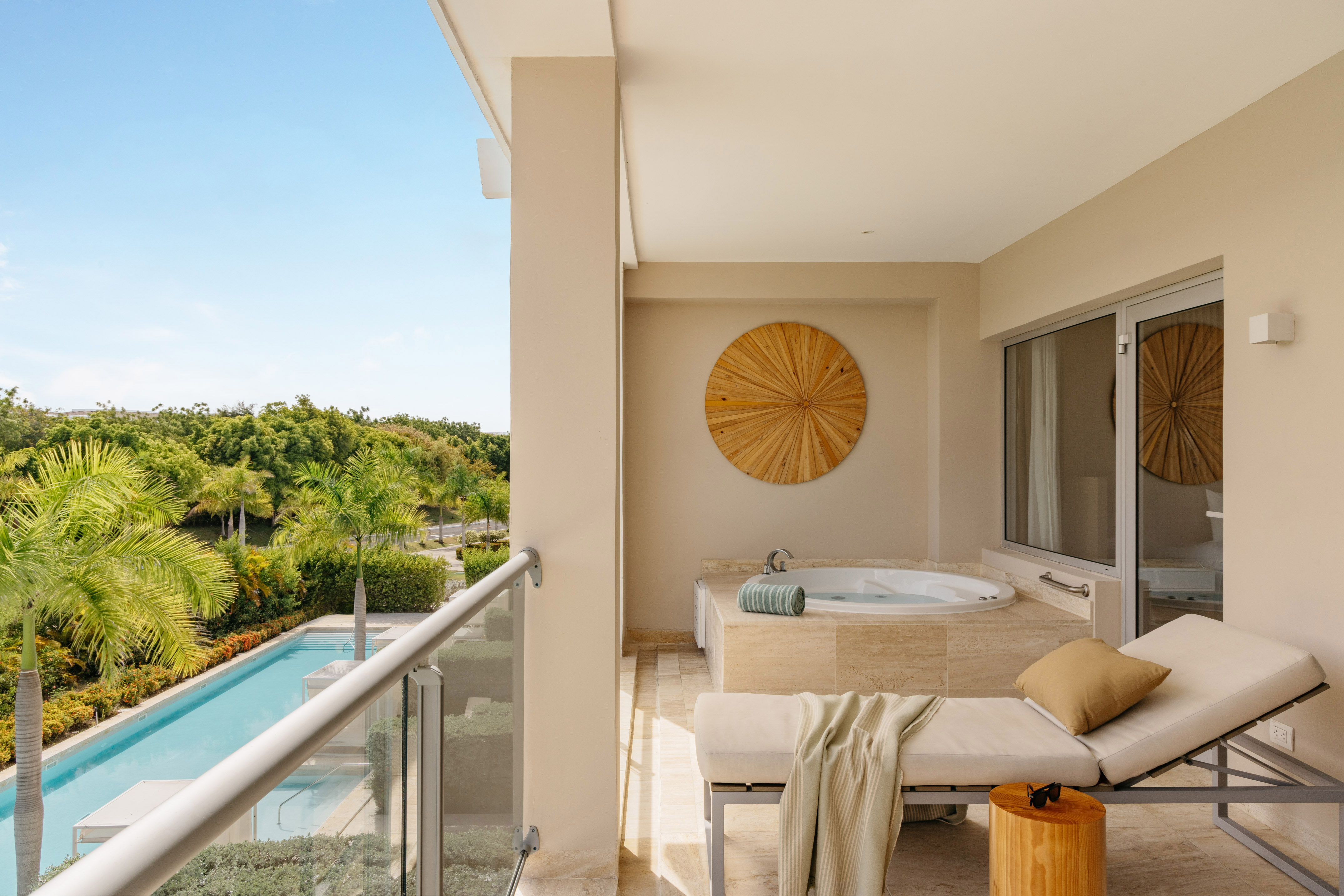 Luxury hotel balcony with private hot tub, daybed, and tropical pool view.