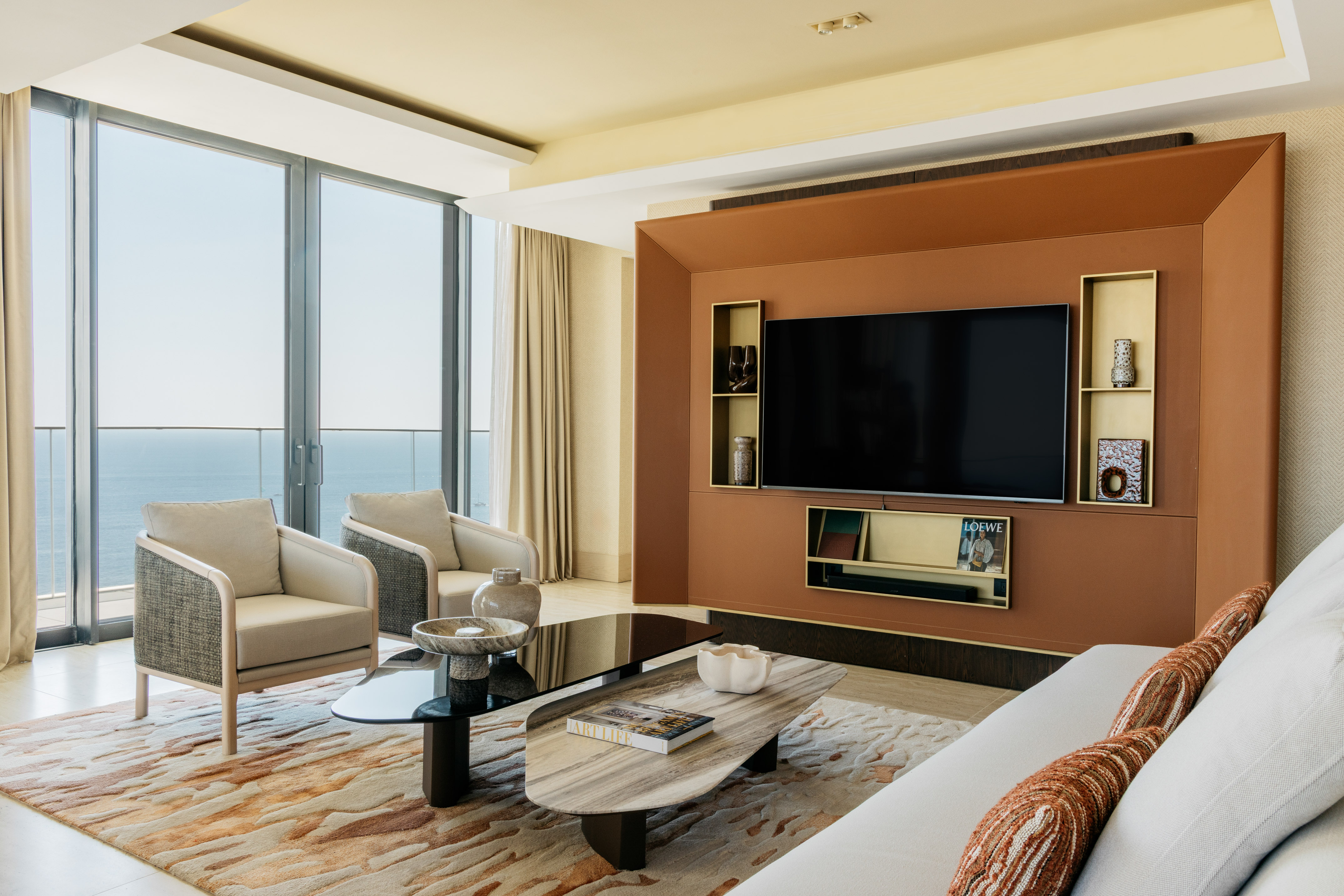 Modern living room with ocean view, contemporary TV wall, and stylish furniture.