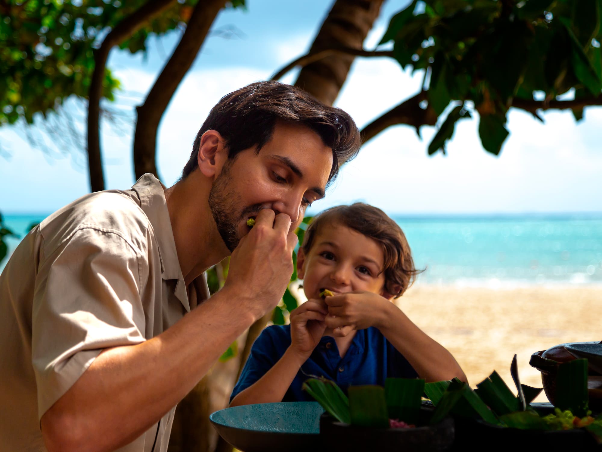 a man and child eating on a beach