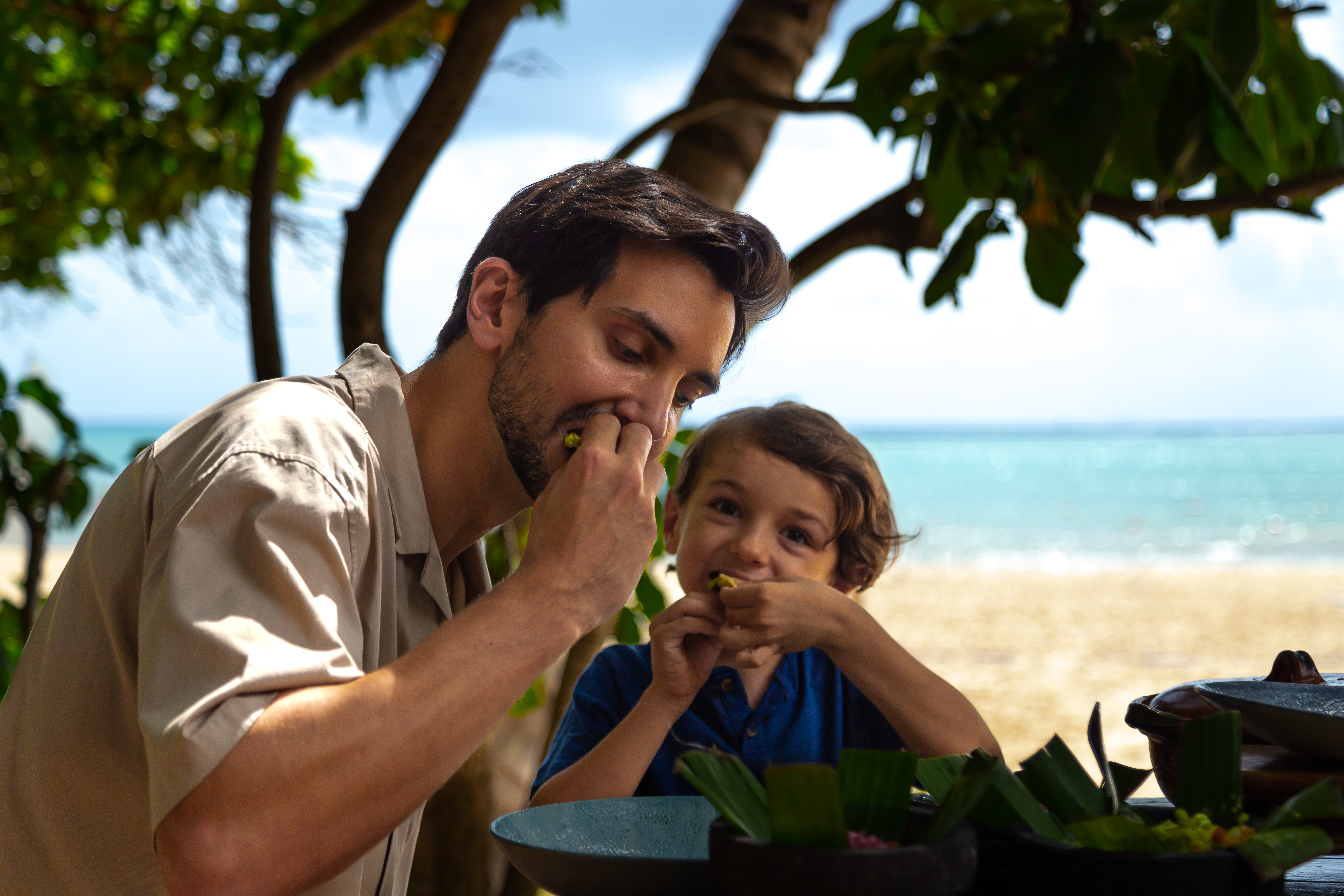 a man and child eating on a beach