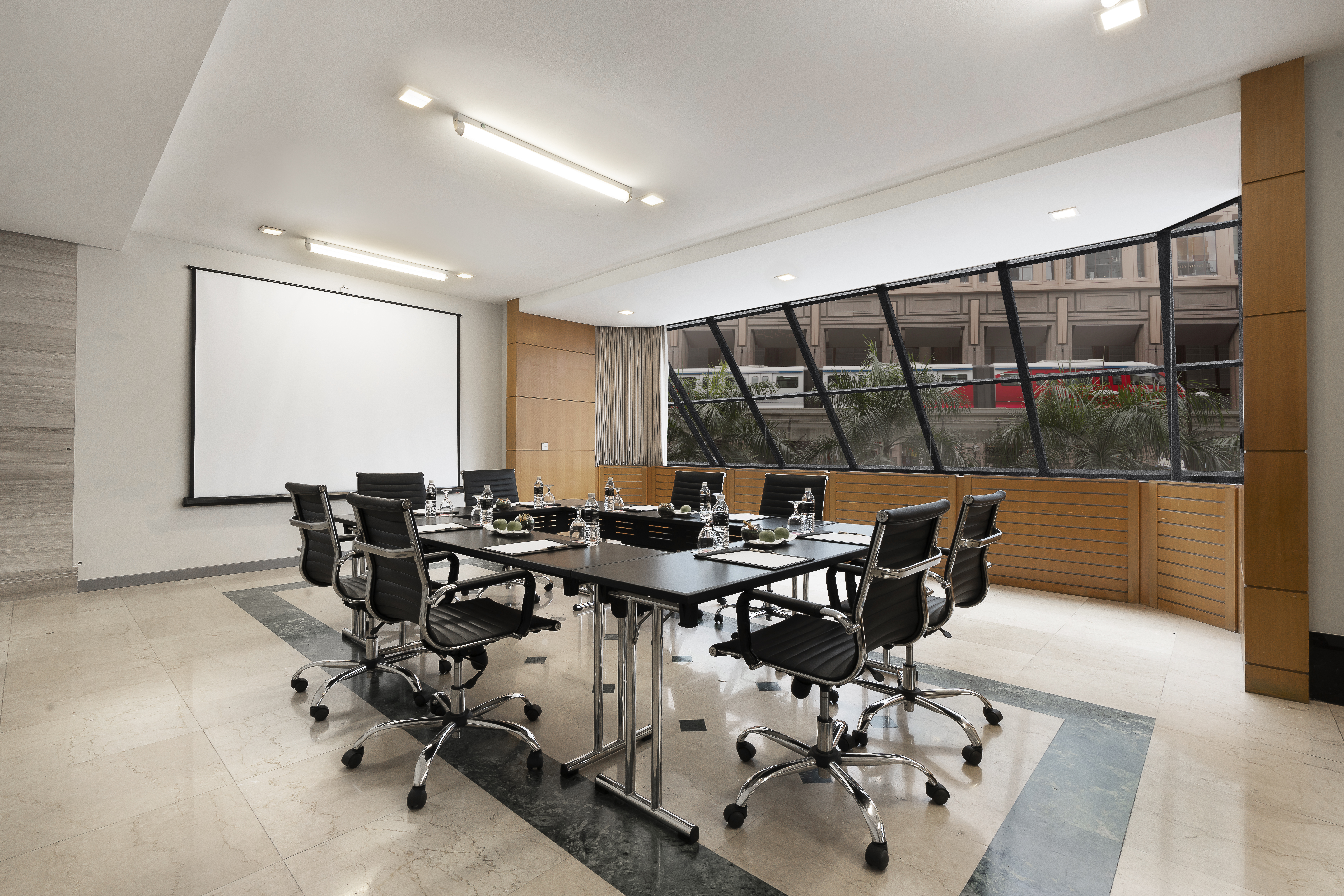 Modern conference room with projector screen, long table, and large windows.