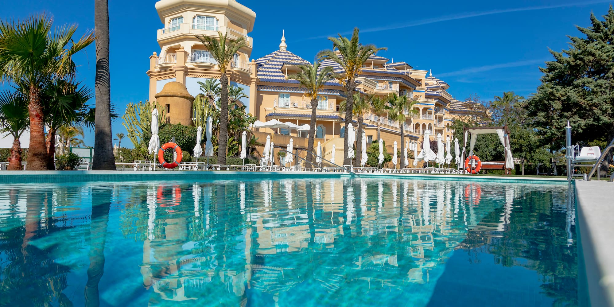 a pool with palm trees and buildings in the background