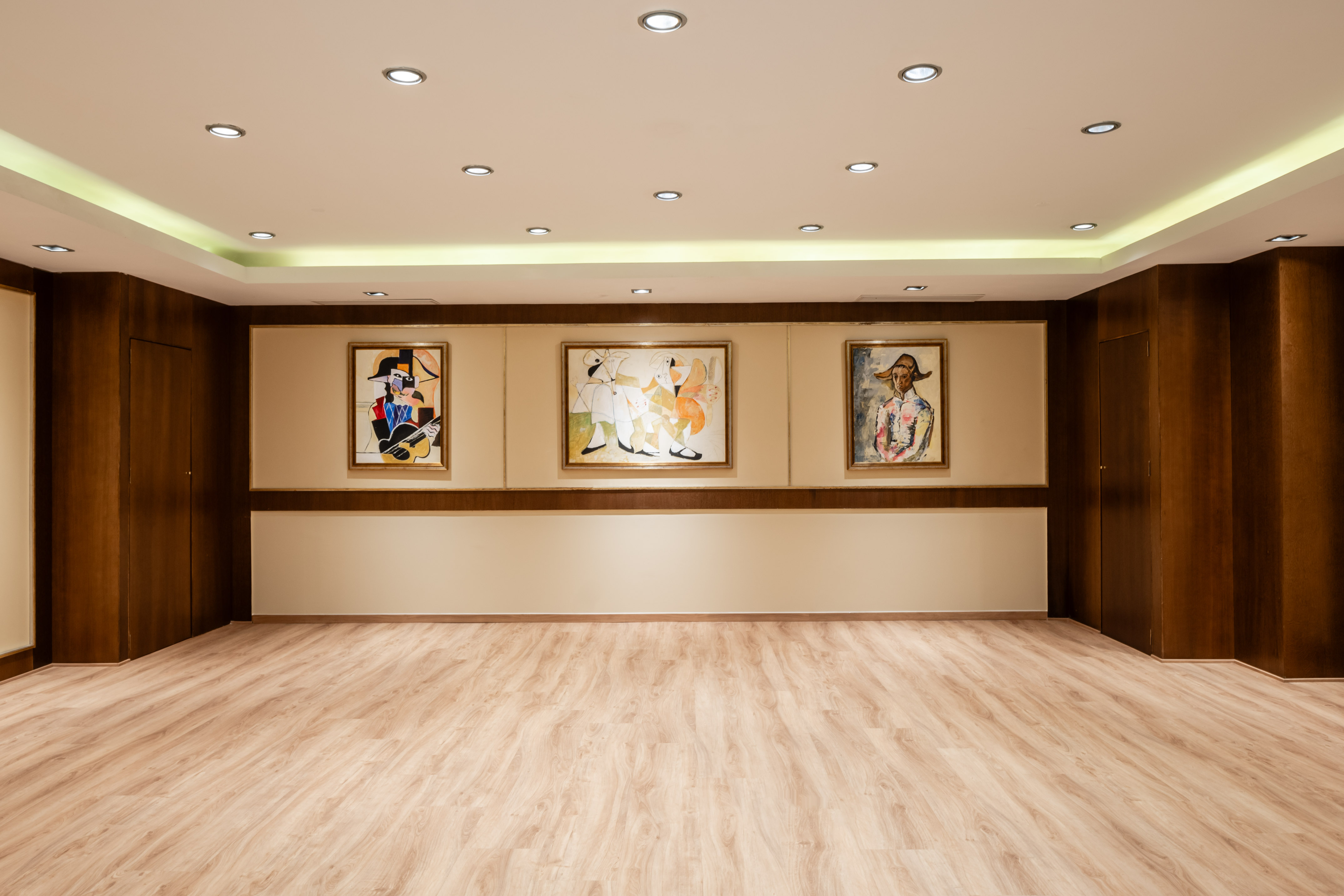 Modern gallery with laminate floor, recessed lighting, and three abstract paintings.